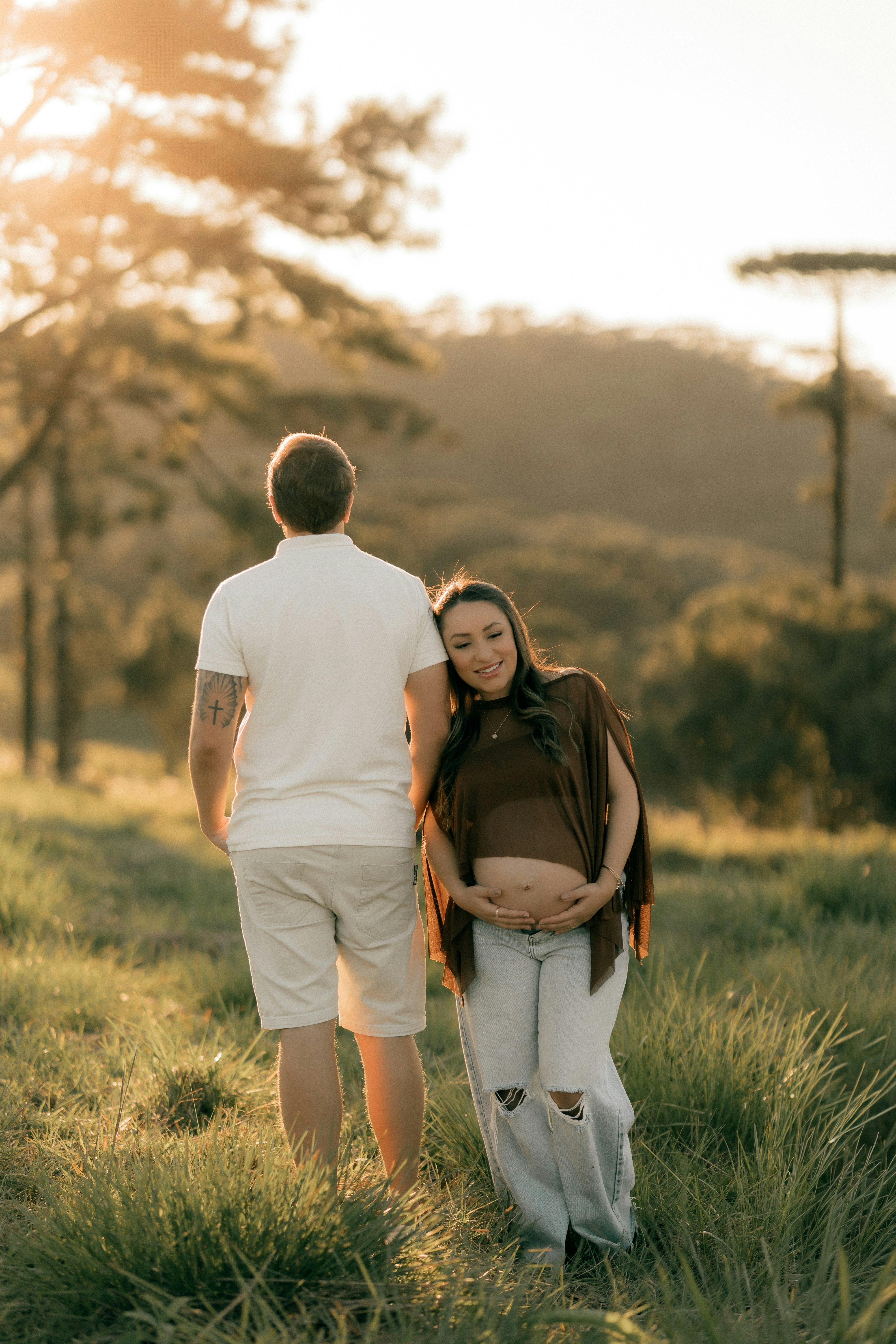 夕暮れの草原に立つ妊婦のカップル