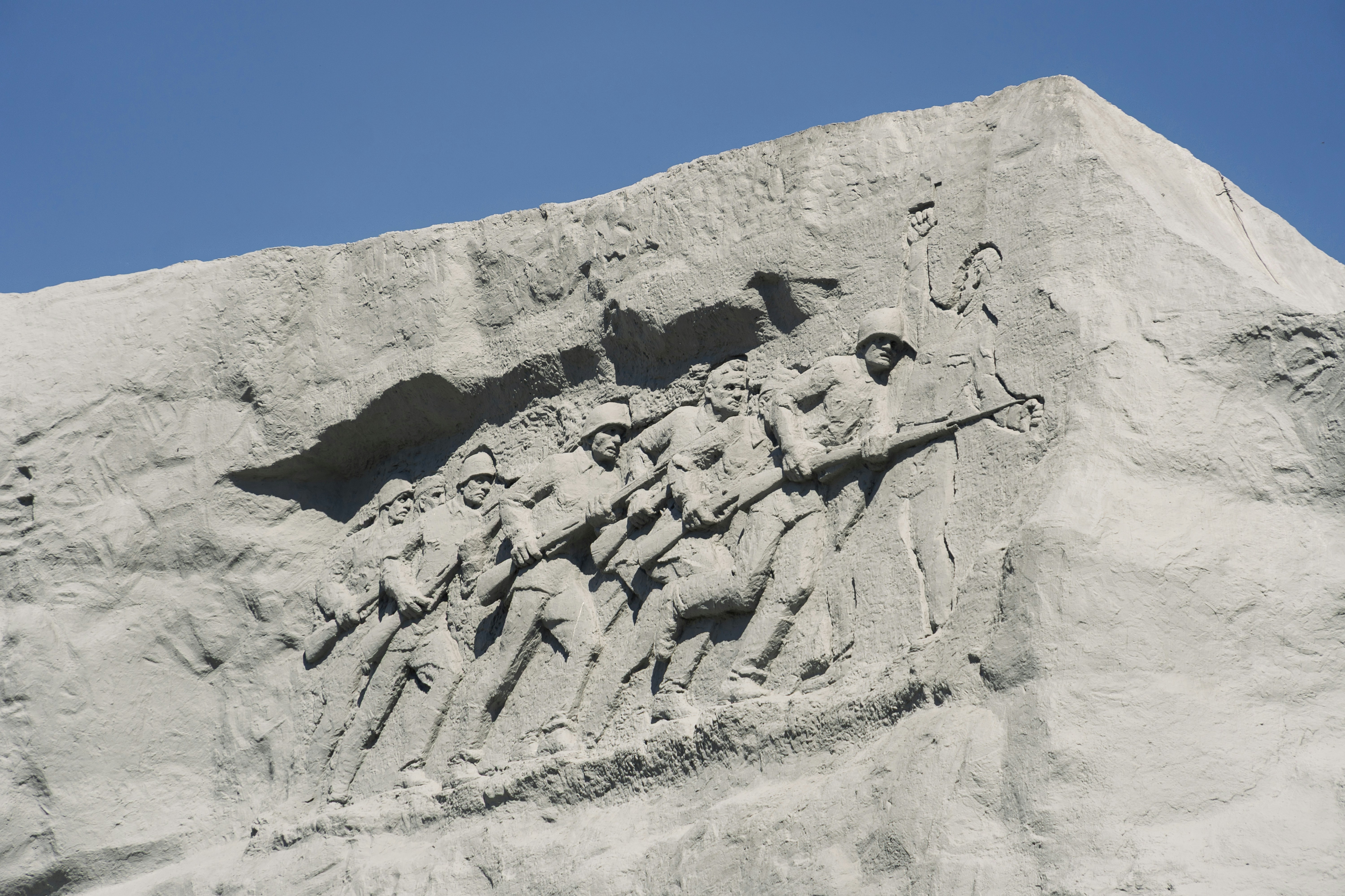 Escultura em relevo de soldados em uma encosta arenosa