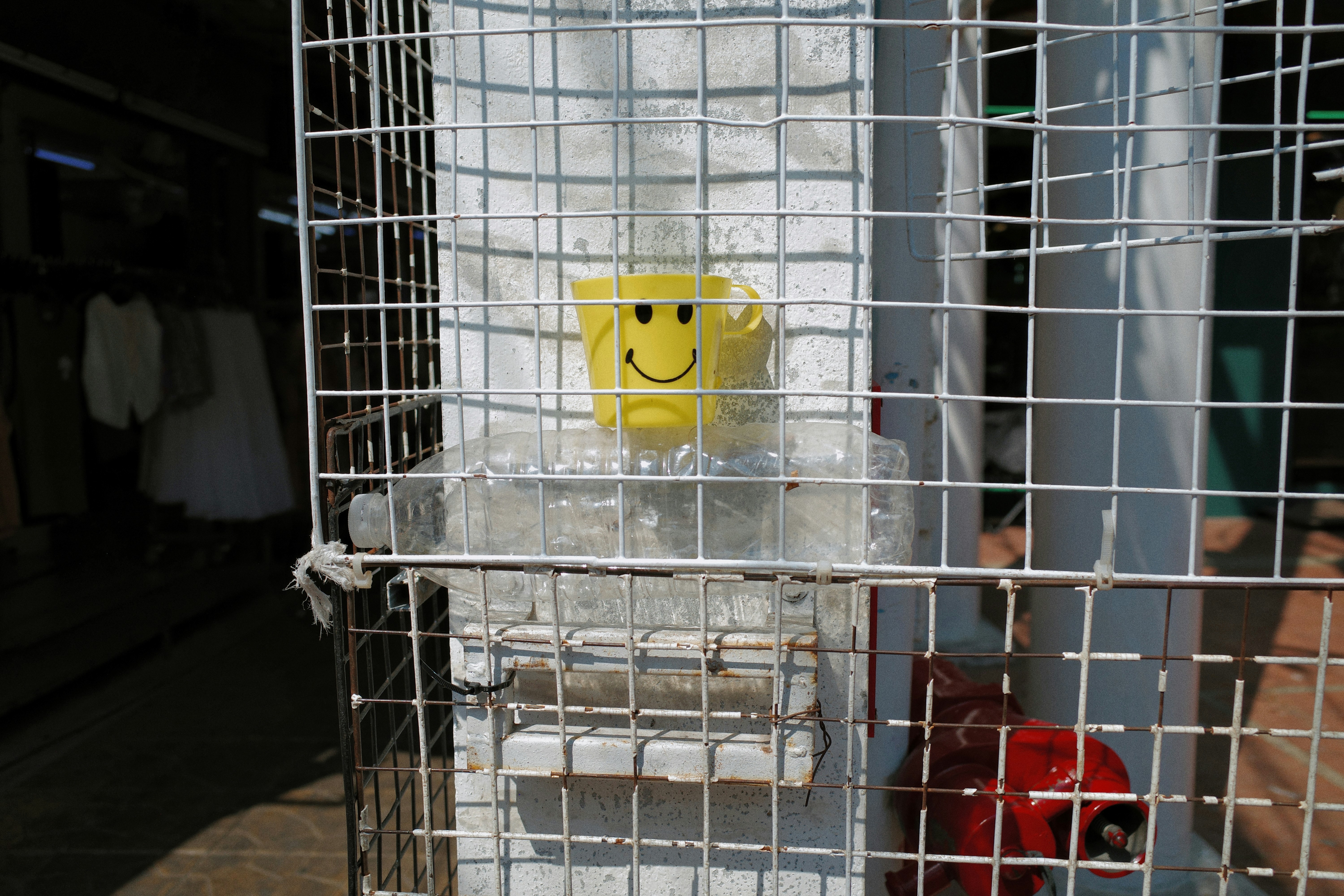 Yellow smiley face cup behind a metal grate