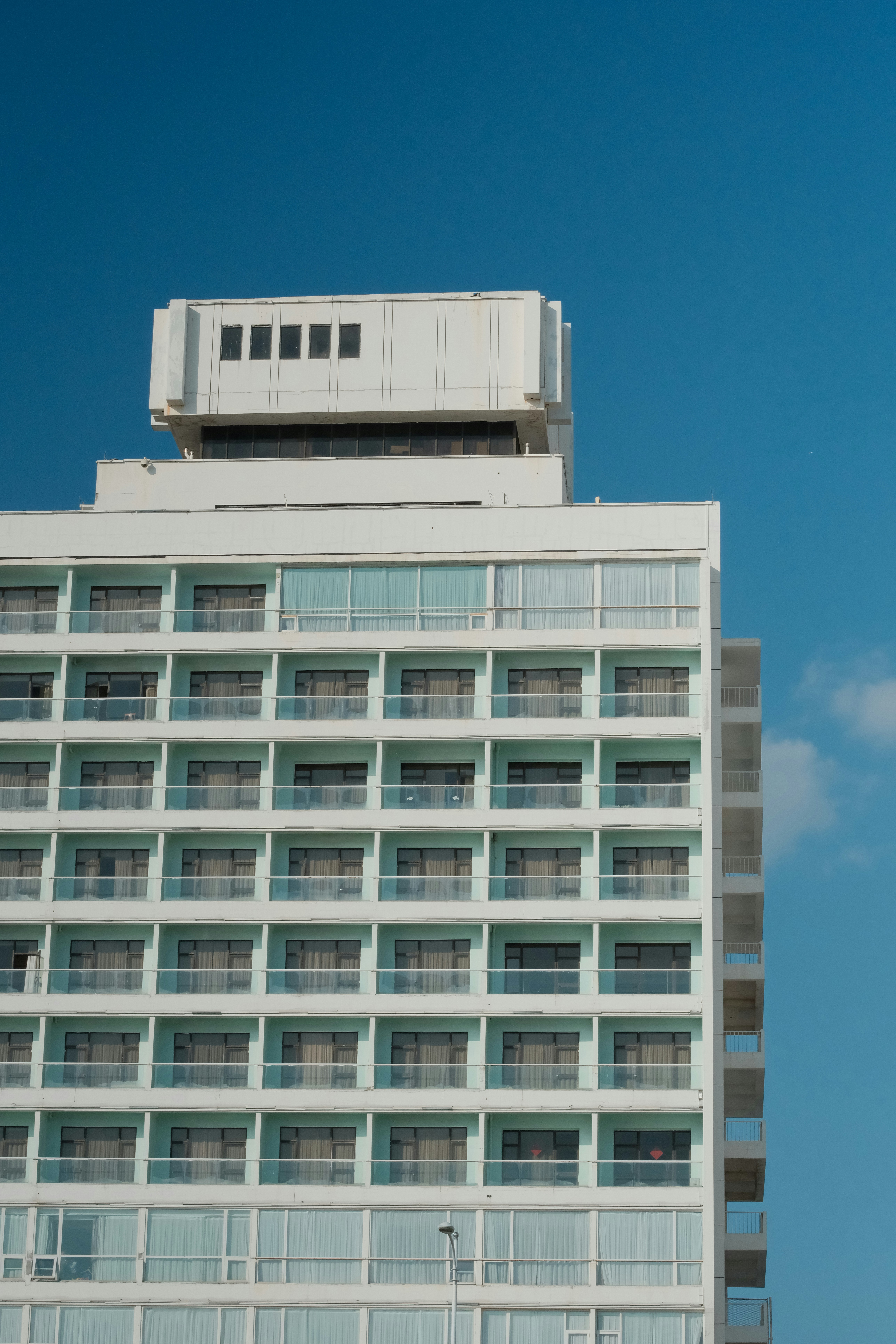 Modern white building with many windows against blue sky