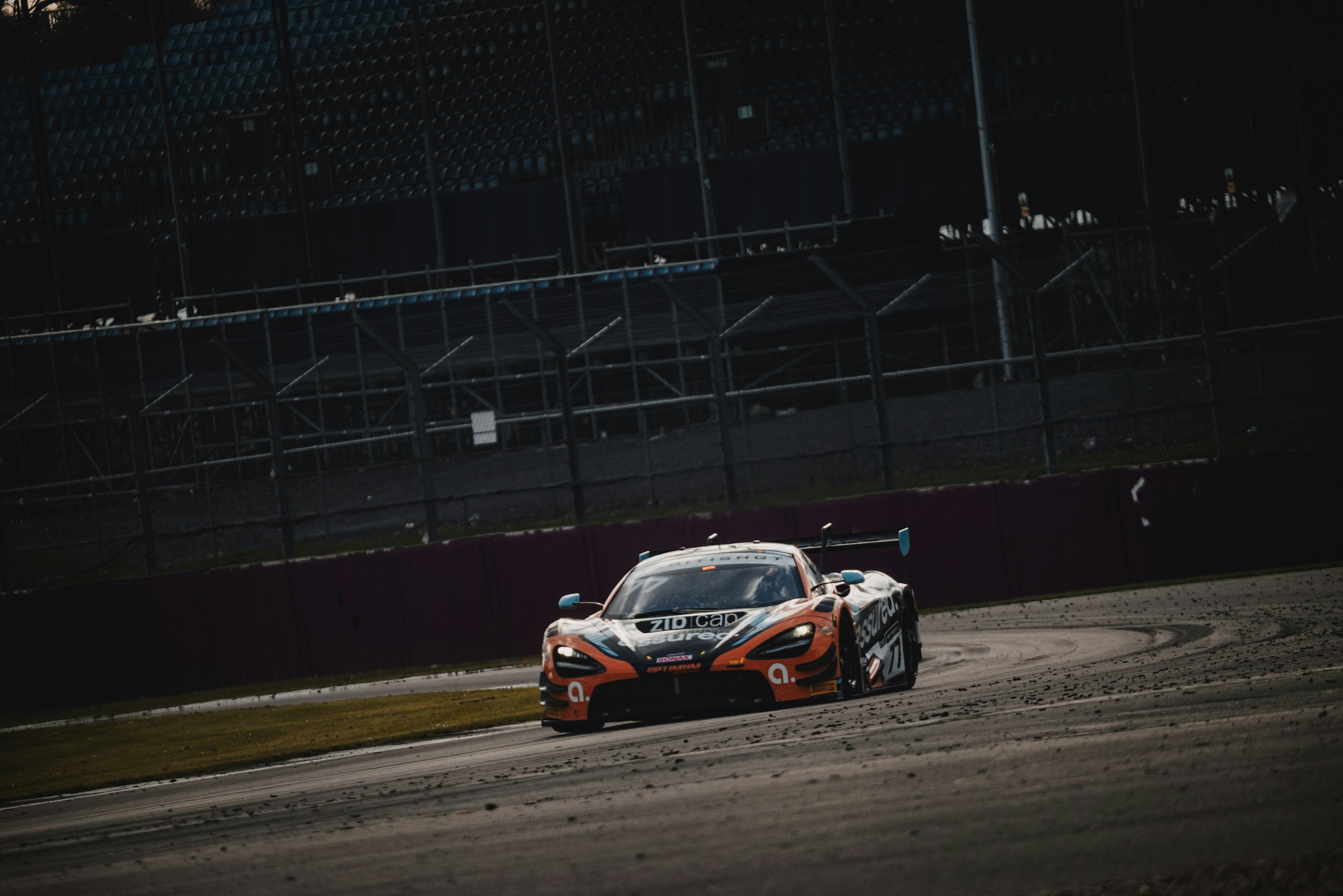 A race car speeds around a track at dusk