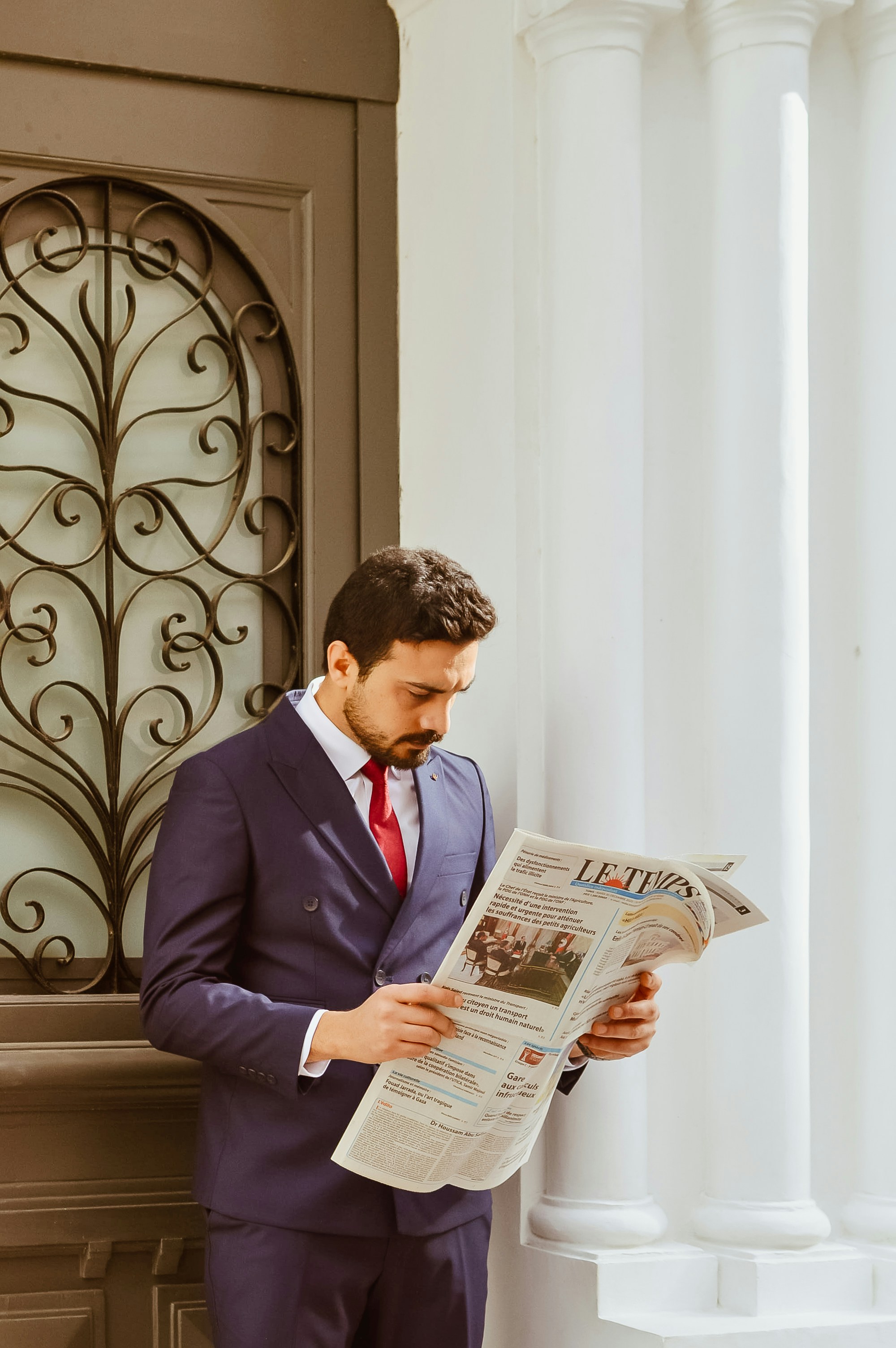 スーツ姿の男が外で新聞を読んでいる