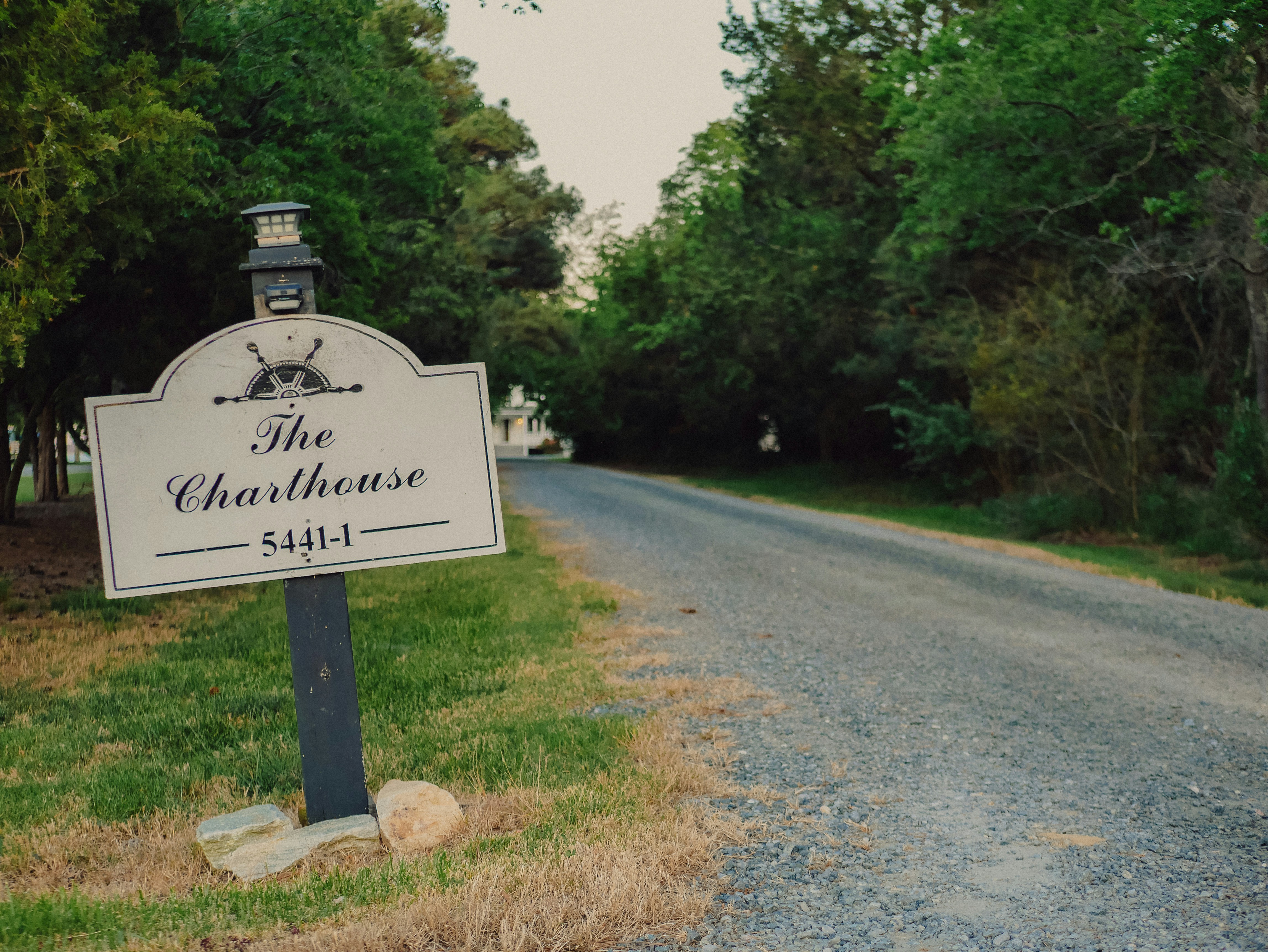 The charthouse sign on a gravel road