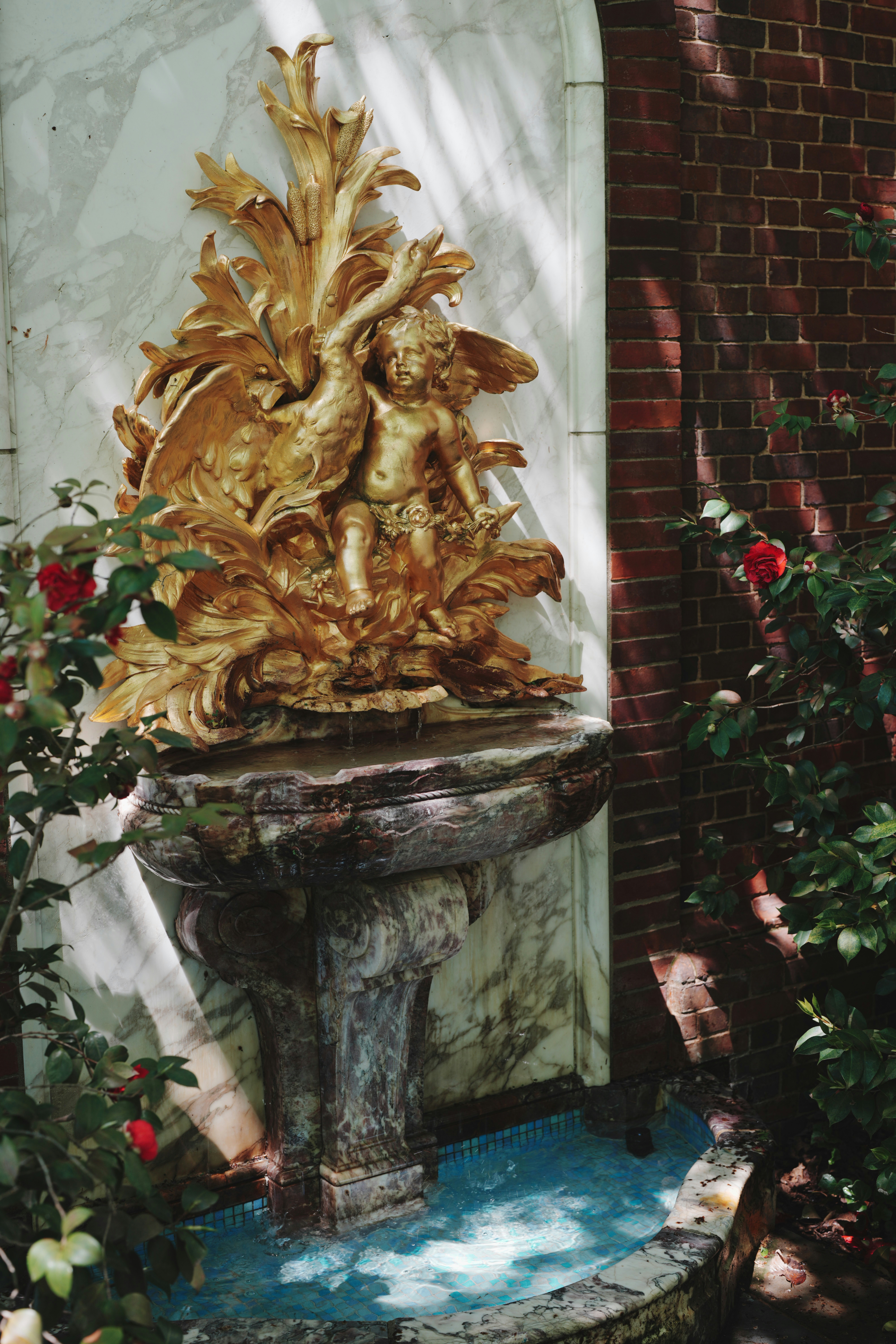 Fonte dourada ornamentada com motivos de querubins e flores.