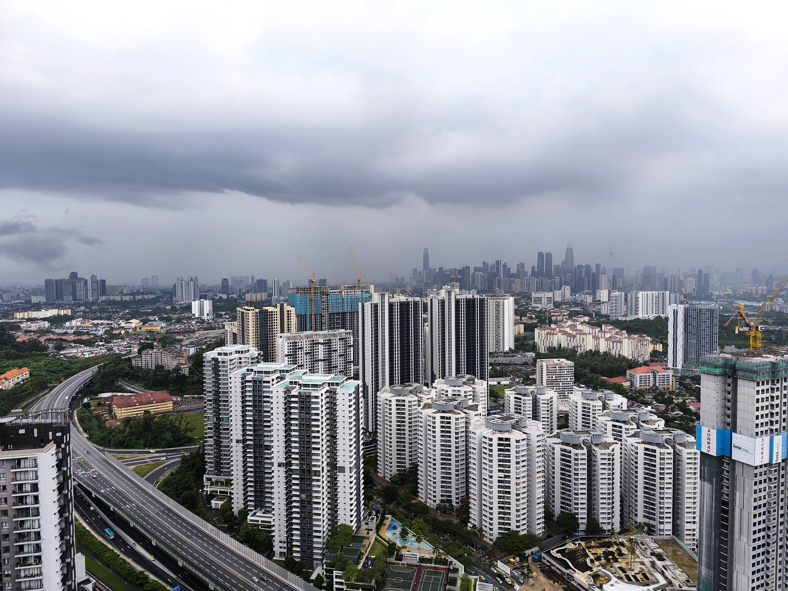 High-rise condominium towers and highways in Kuala Lumpur under a cloudy sky