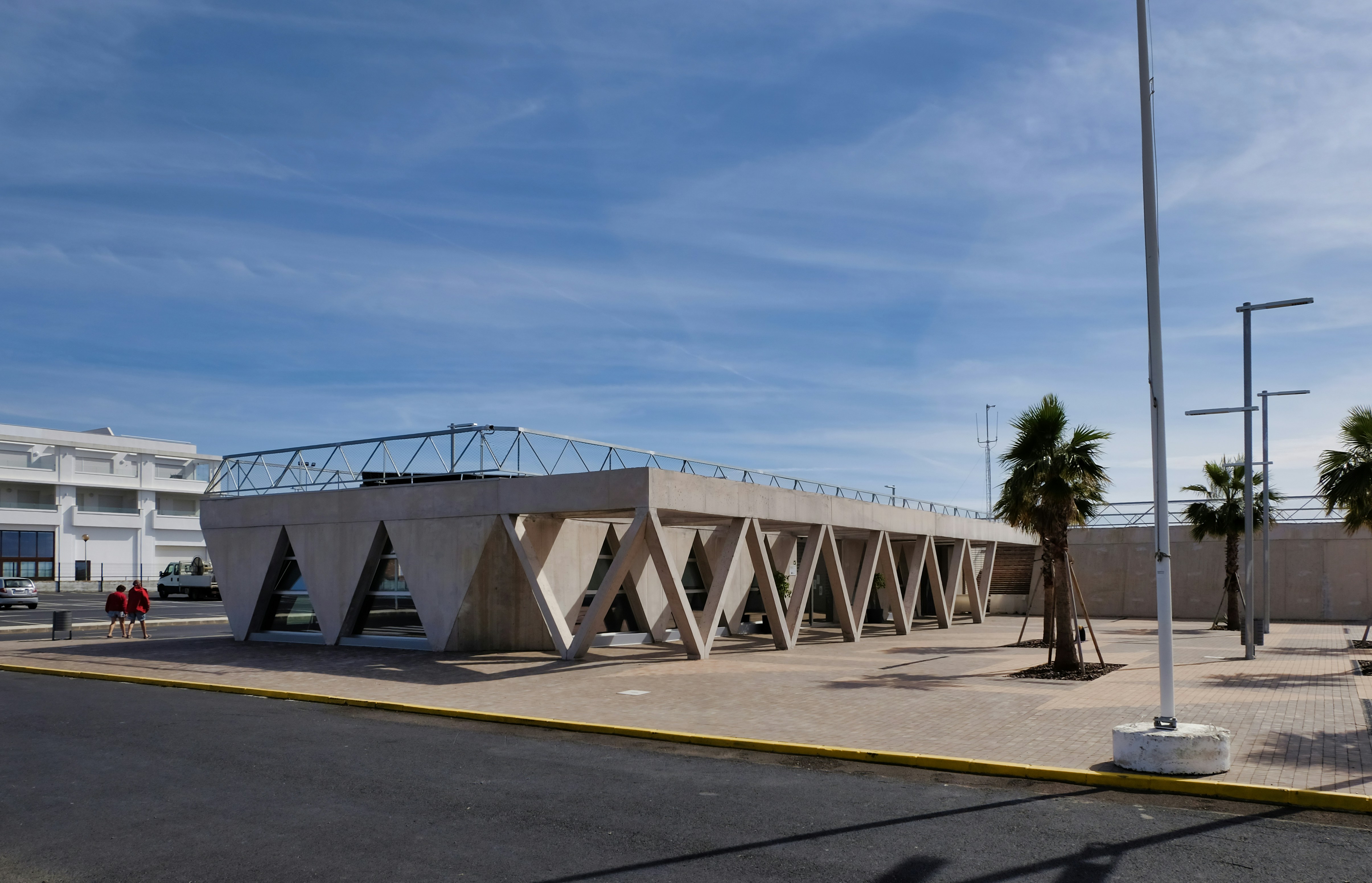 Bâtiment moderne en béton avec des supports triangulaires sous le ciel.