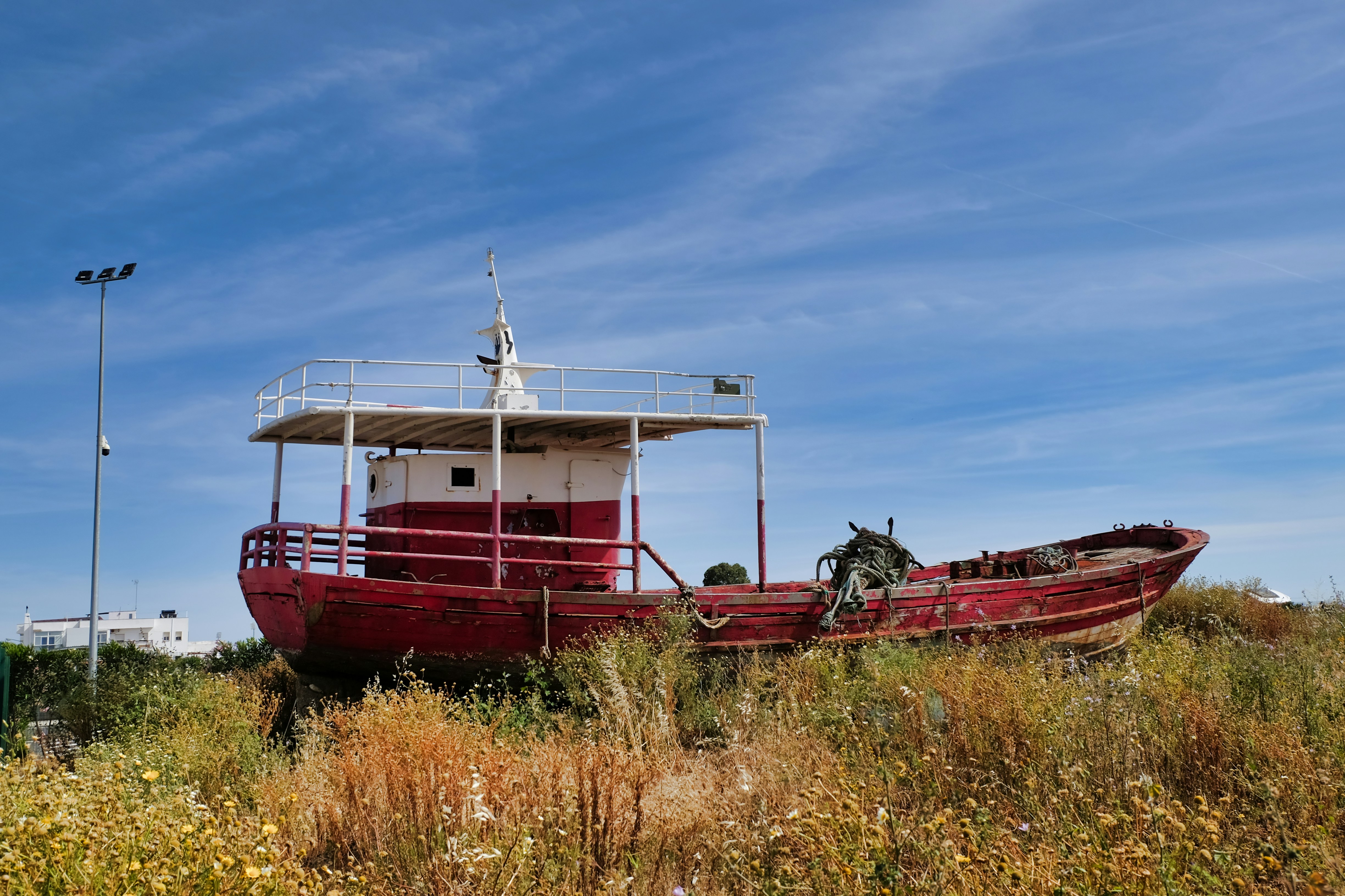 Bateau de pêche rouge et blanc reposant sur la terre ferme