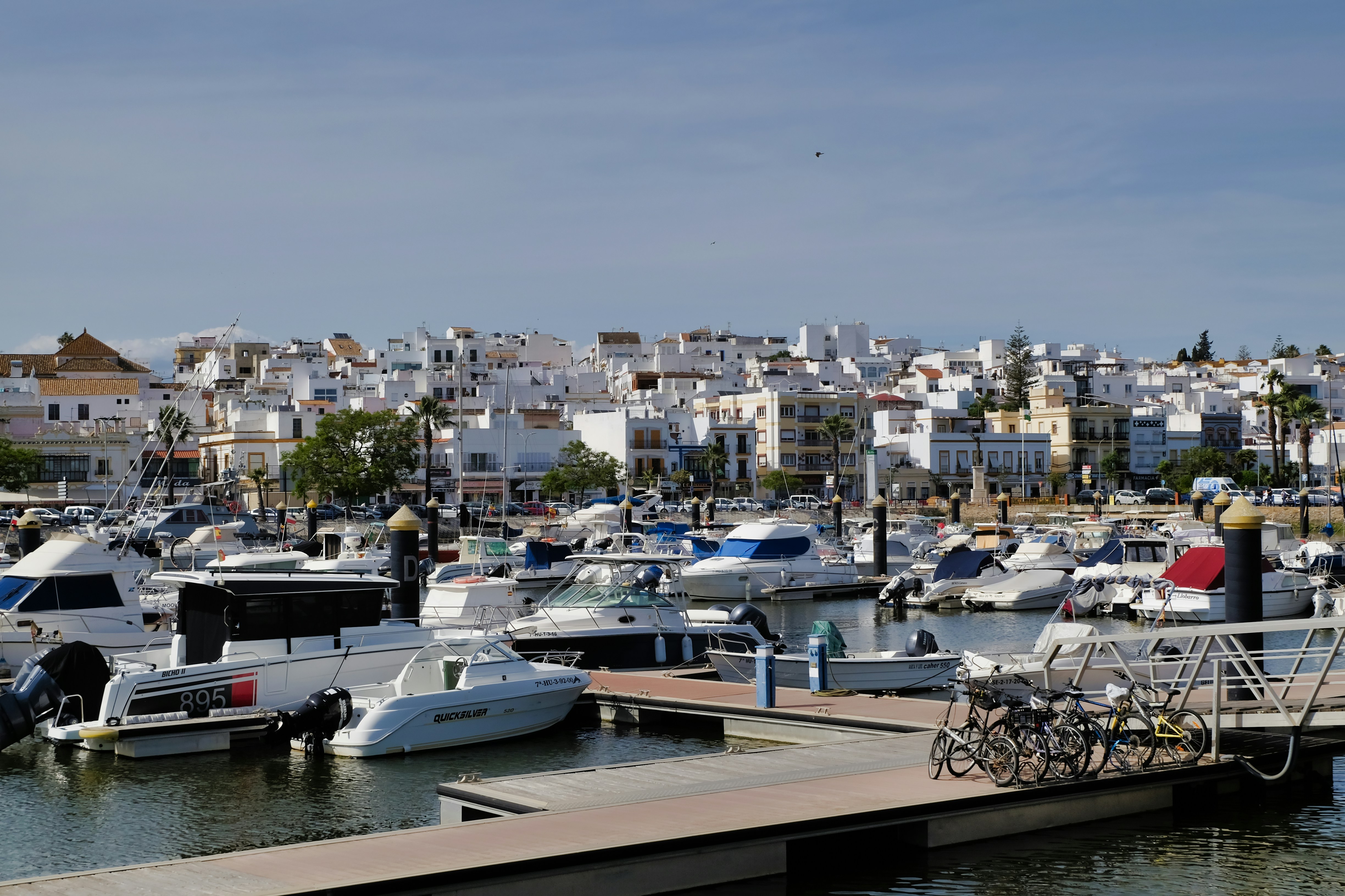 Des bateaux accostés dans un port ensoleillé aux bâtiments blancs.
