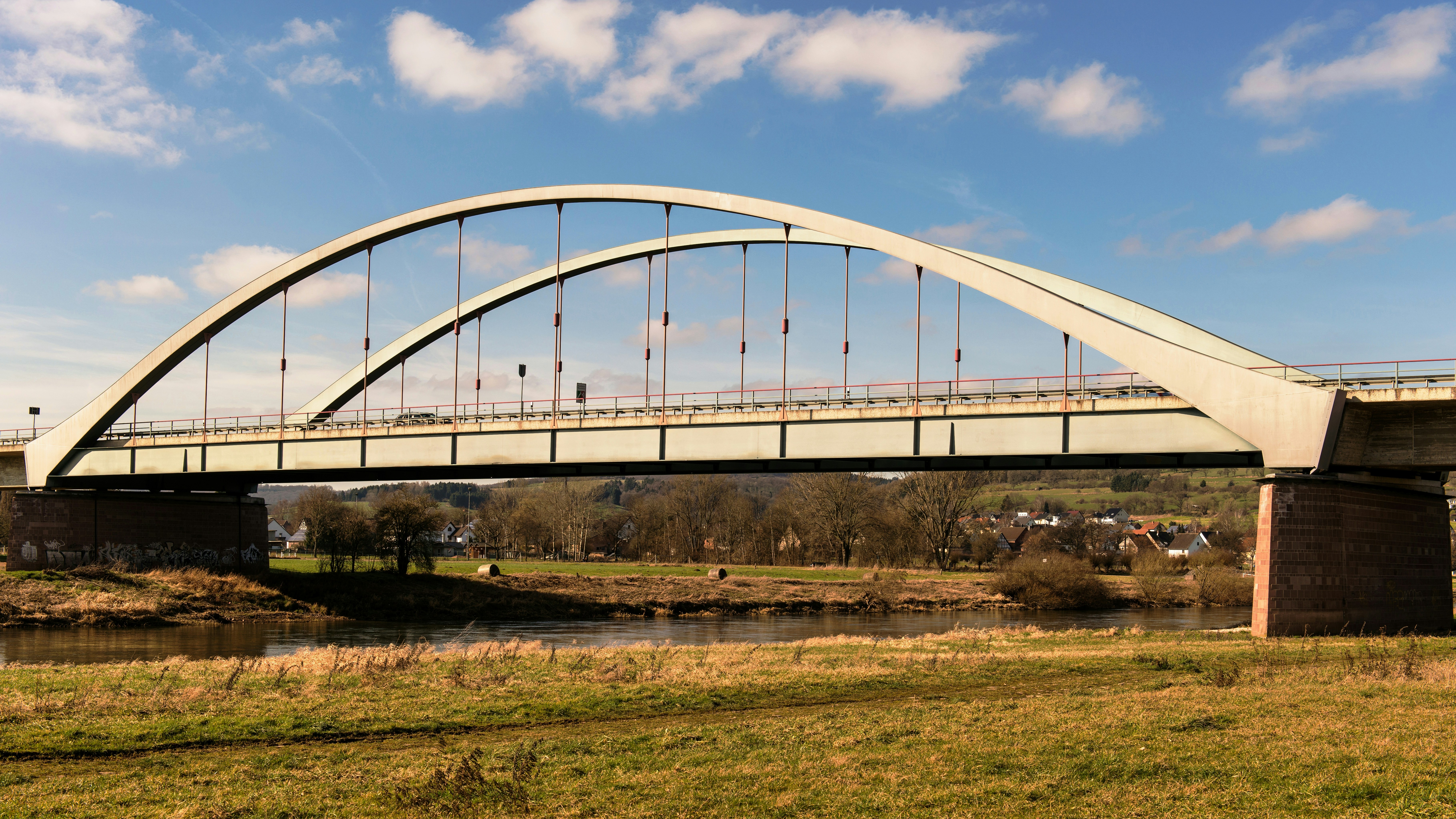 Puente de arco moderno sobre un río con orillas cubiertas de hierba
