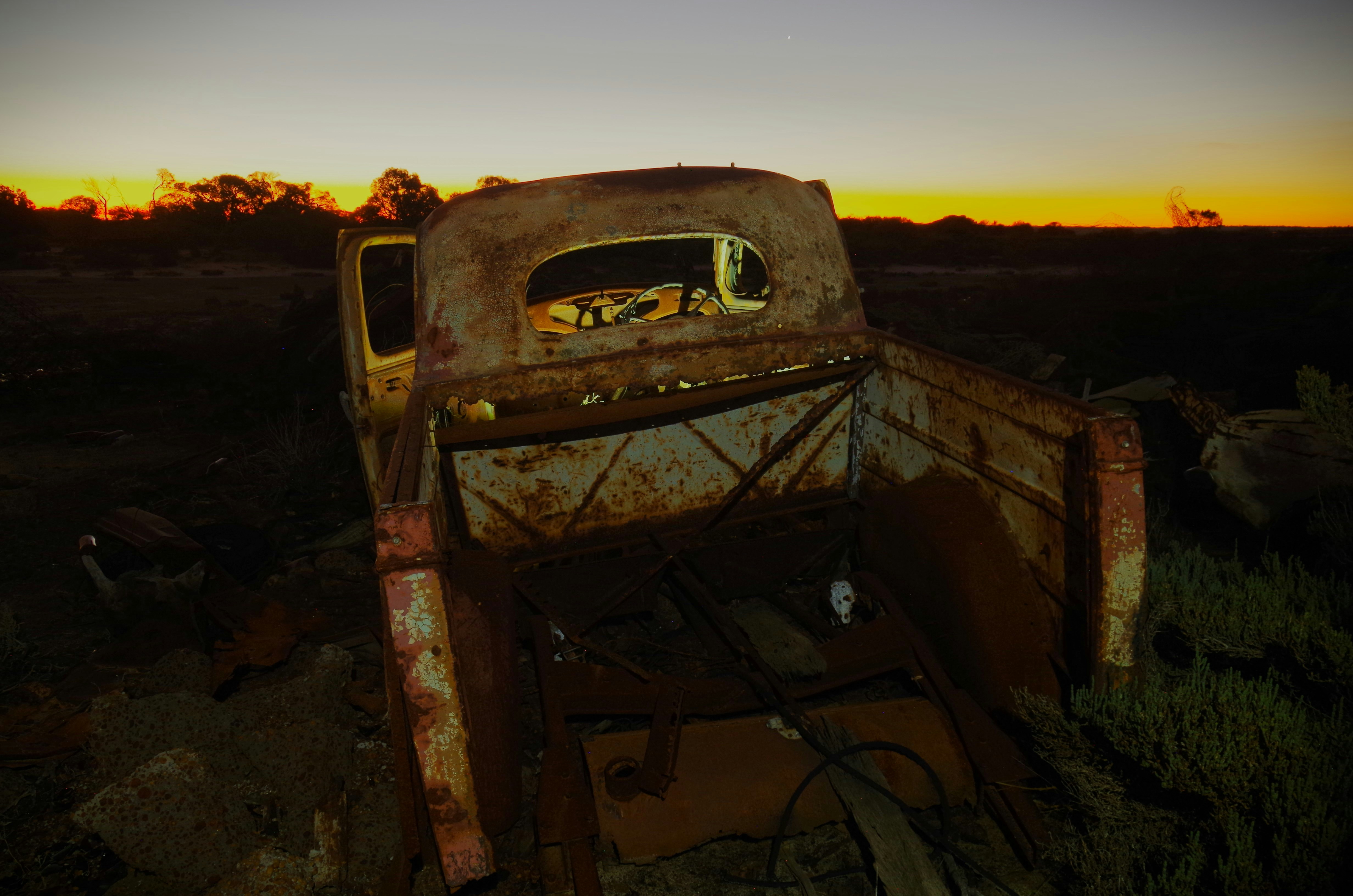 Caminhão velho e enferrujado em um campo ao pôr do sol