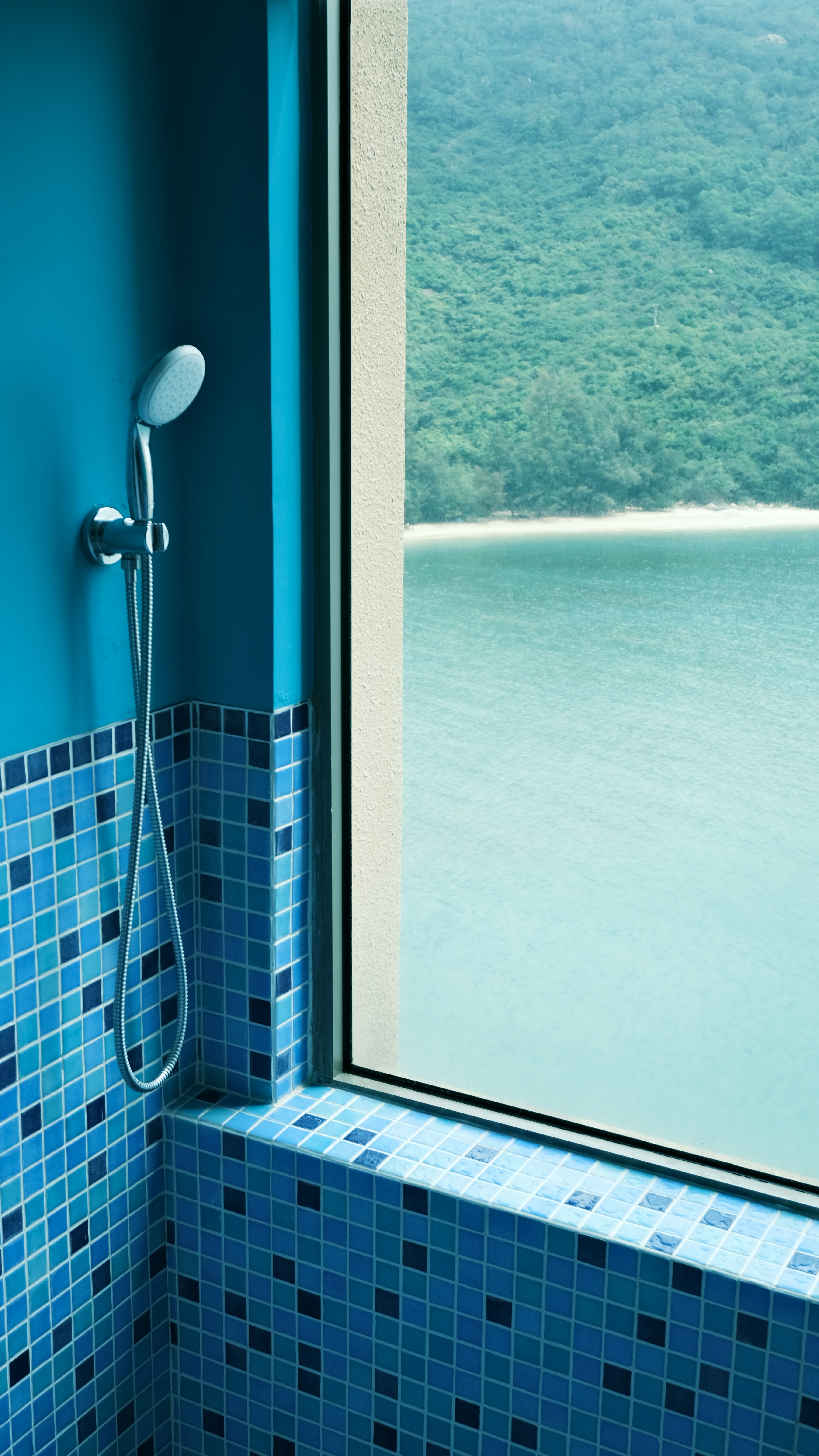 Shower with ocean view and green hills beyond