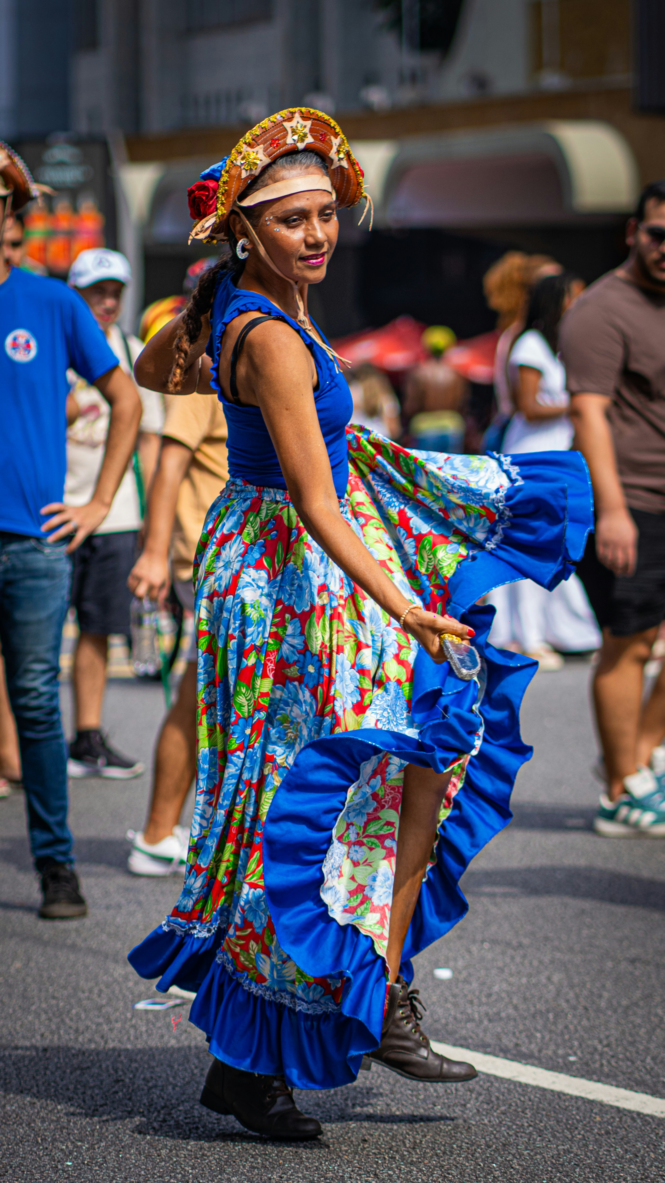 Mulher com vestidos coloridos dançando em um festival de rua.