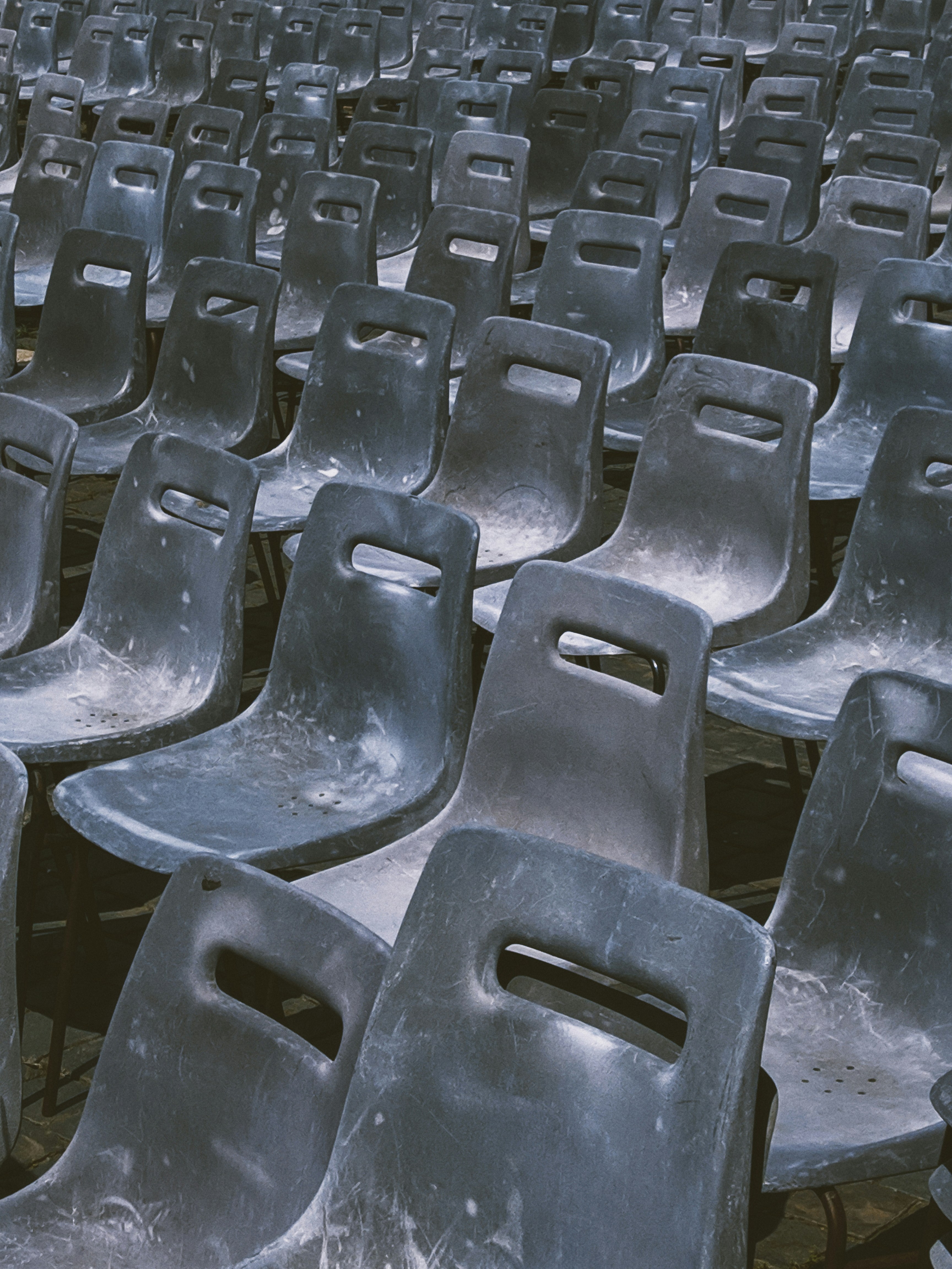 Rangées de chaises en plastique sombre vides à l’extérieur