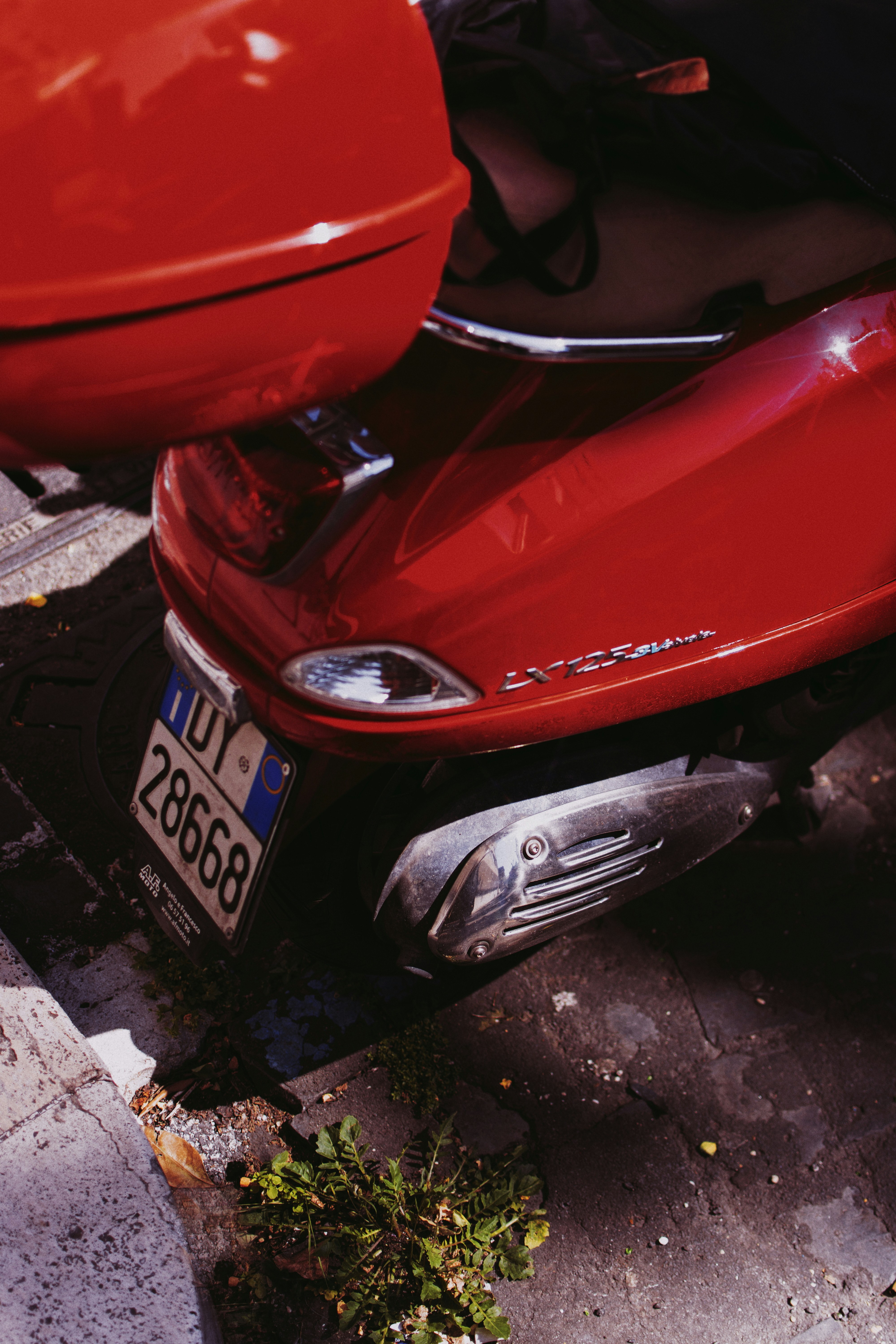 Scooter rojo aparcado en una calle empedrada.