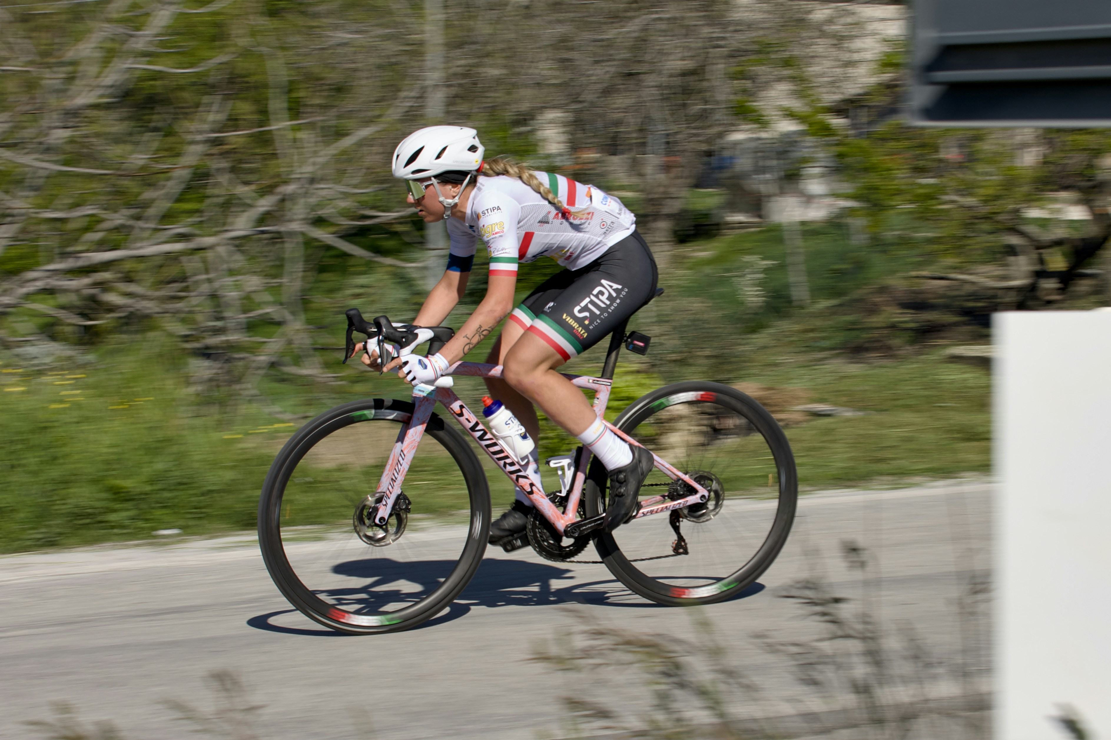 A cyclist races downhill on a paved road.