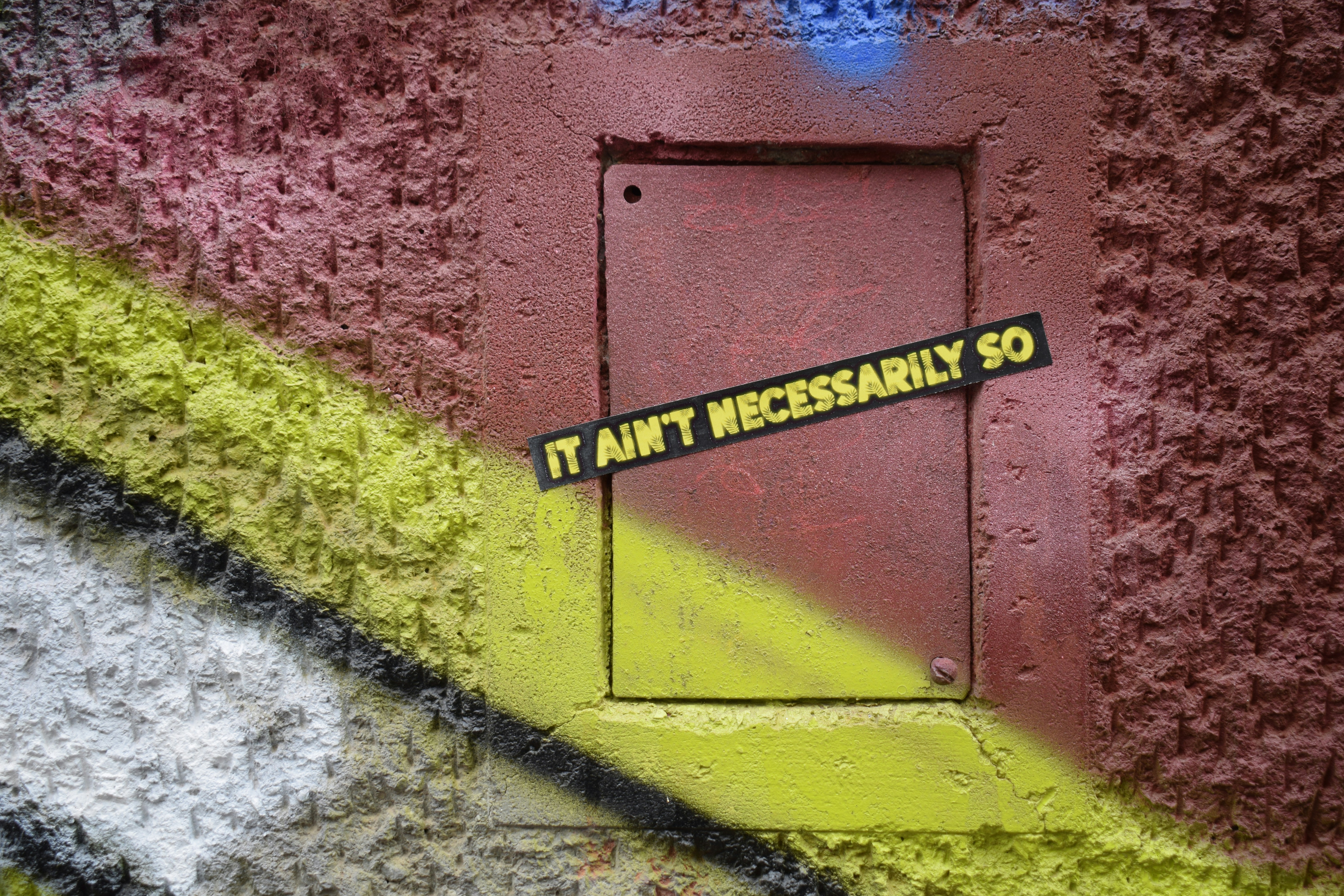 Graffiti on a wall with a small metal door.