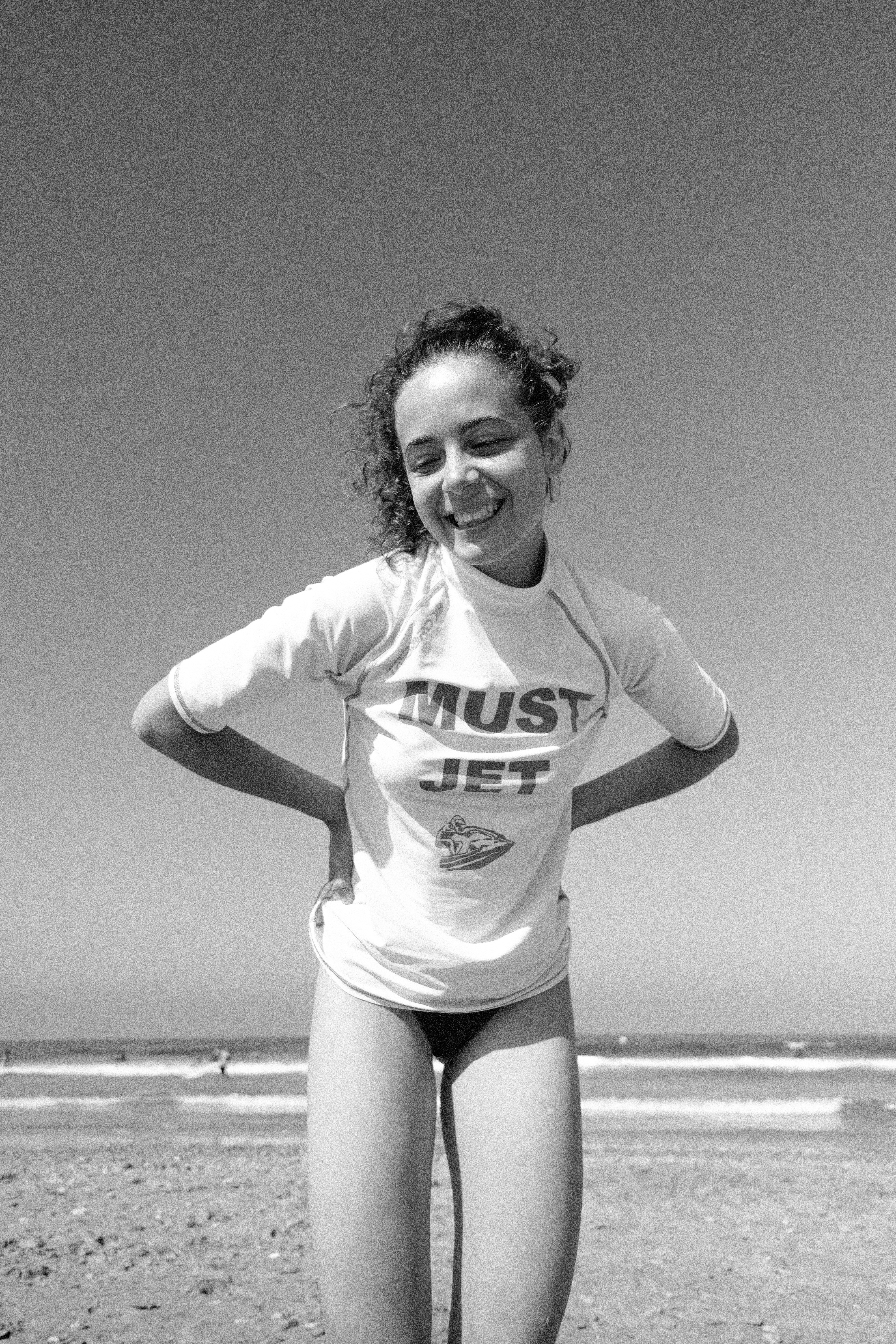 Giovane donna sorridente su una spiaggia, in bianco e nero.