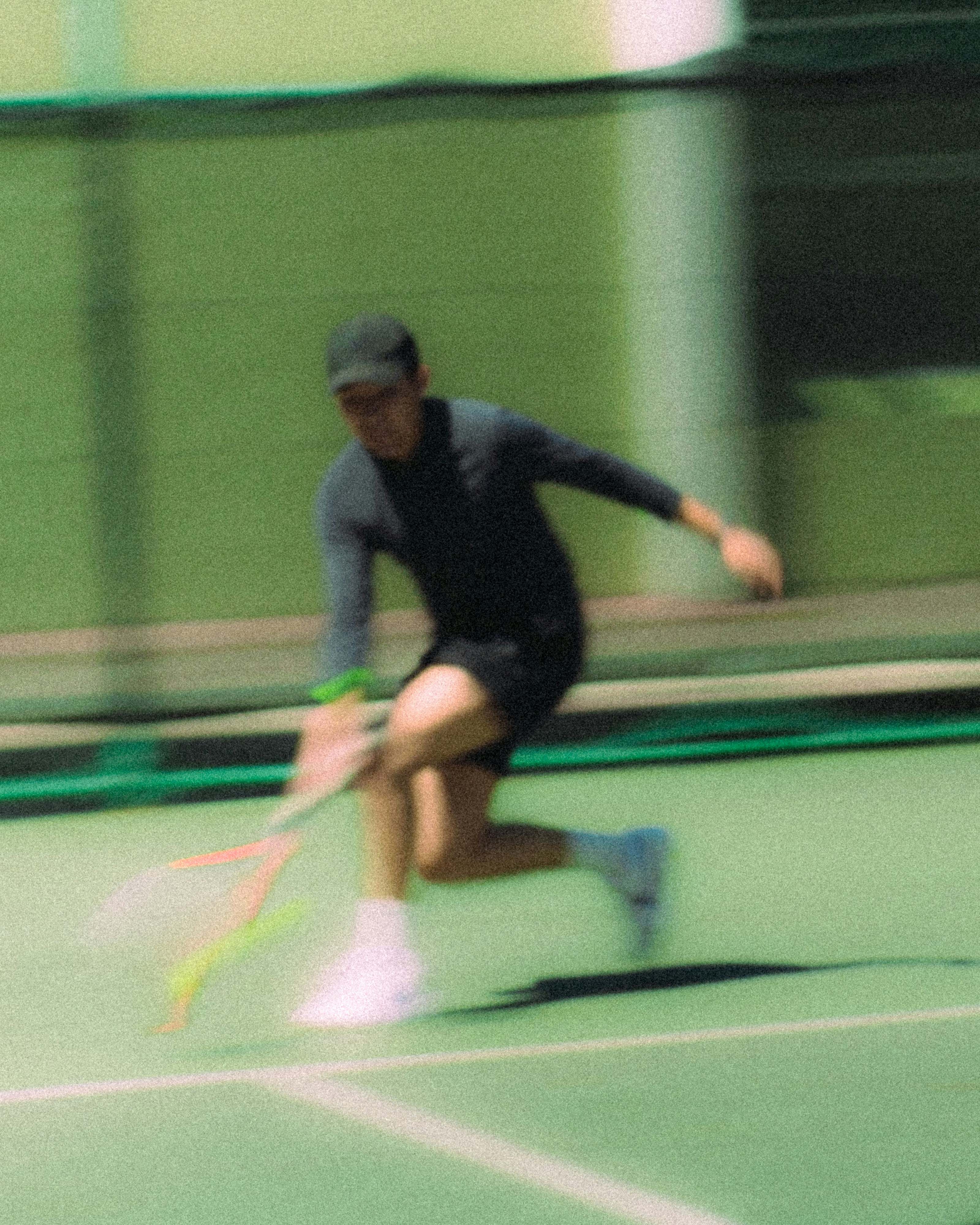 Tennis player in motion on a green court.
