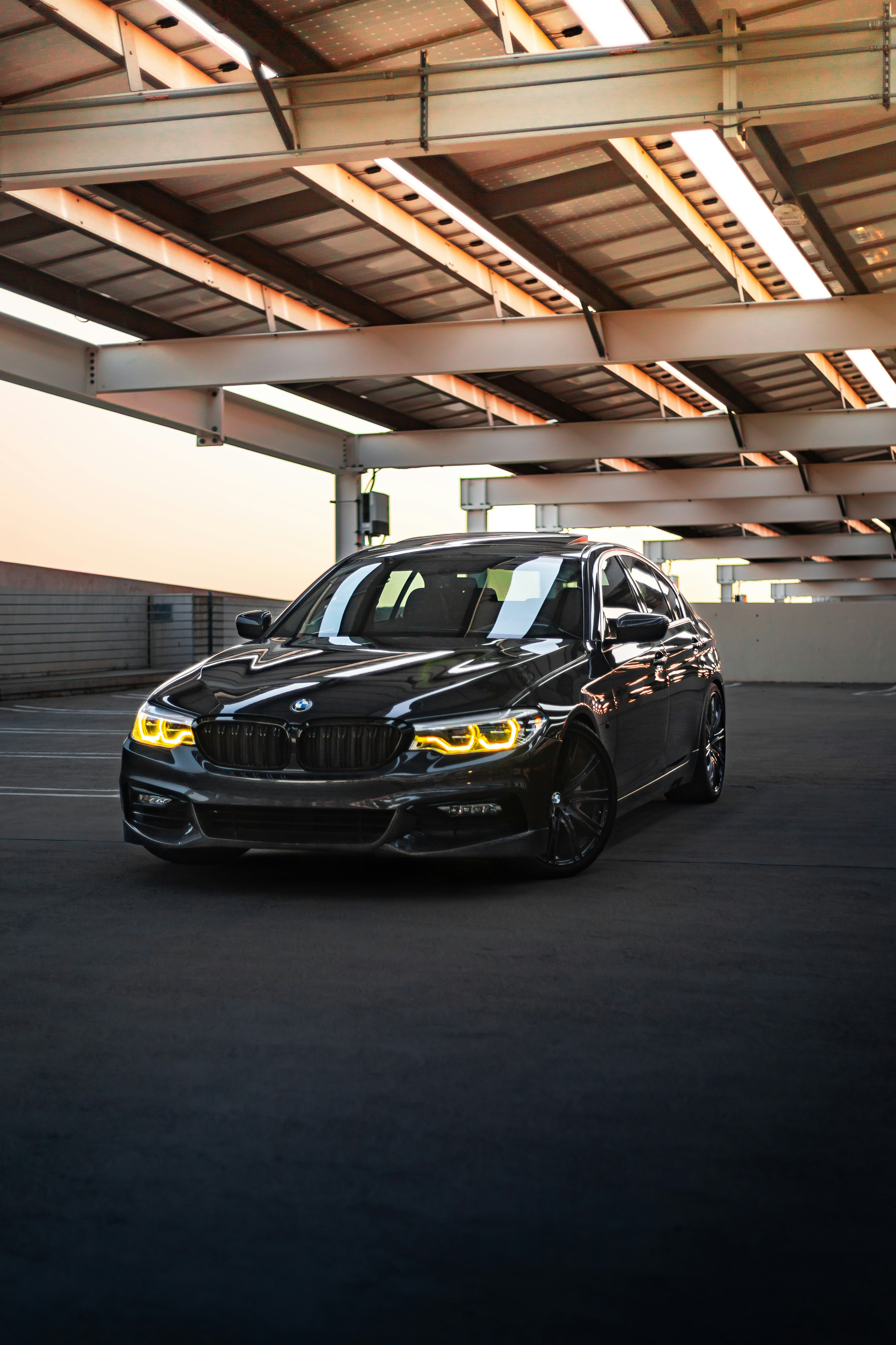 A black BMW sedan parked under a metal structure.
