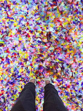 A person standing in a large pile of colorful confetti.