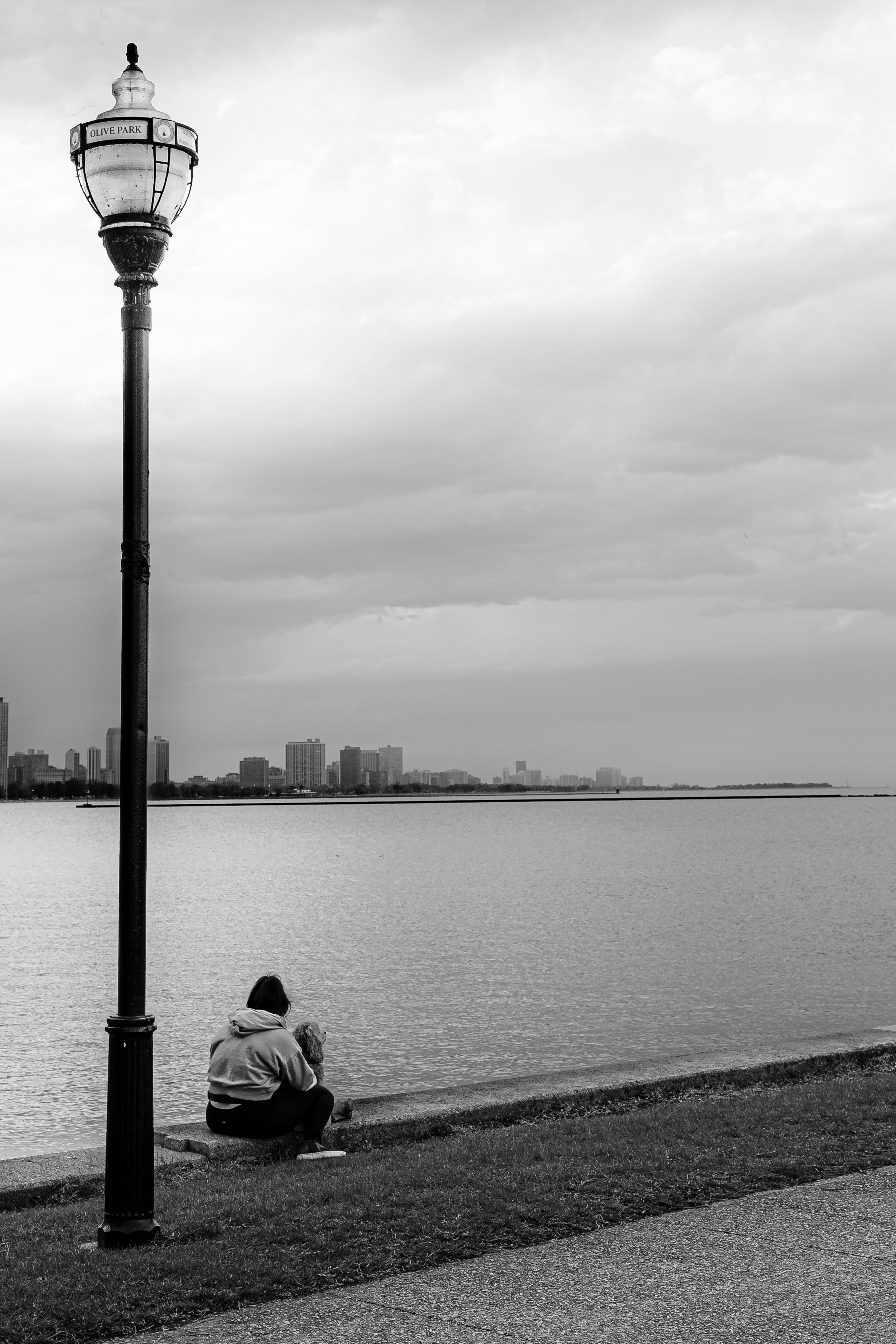 Person sitzt am Wasser mit Stadtsilhouette