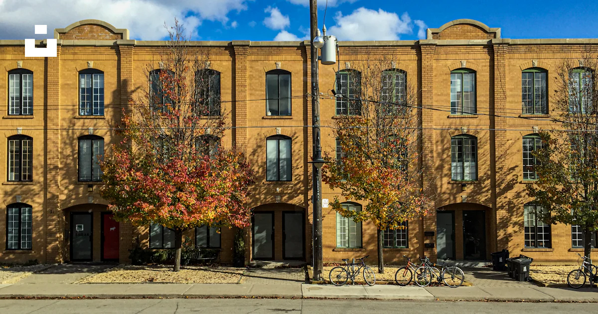 Brick building with arched doorways and autumn trees photo – Free Real ...