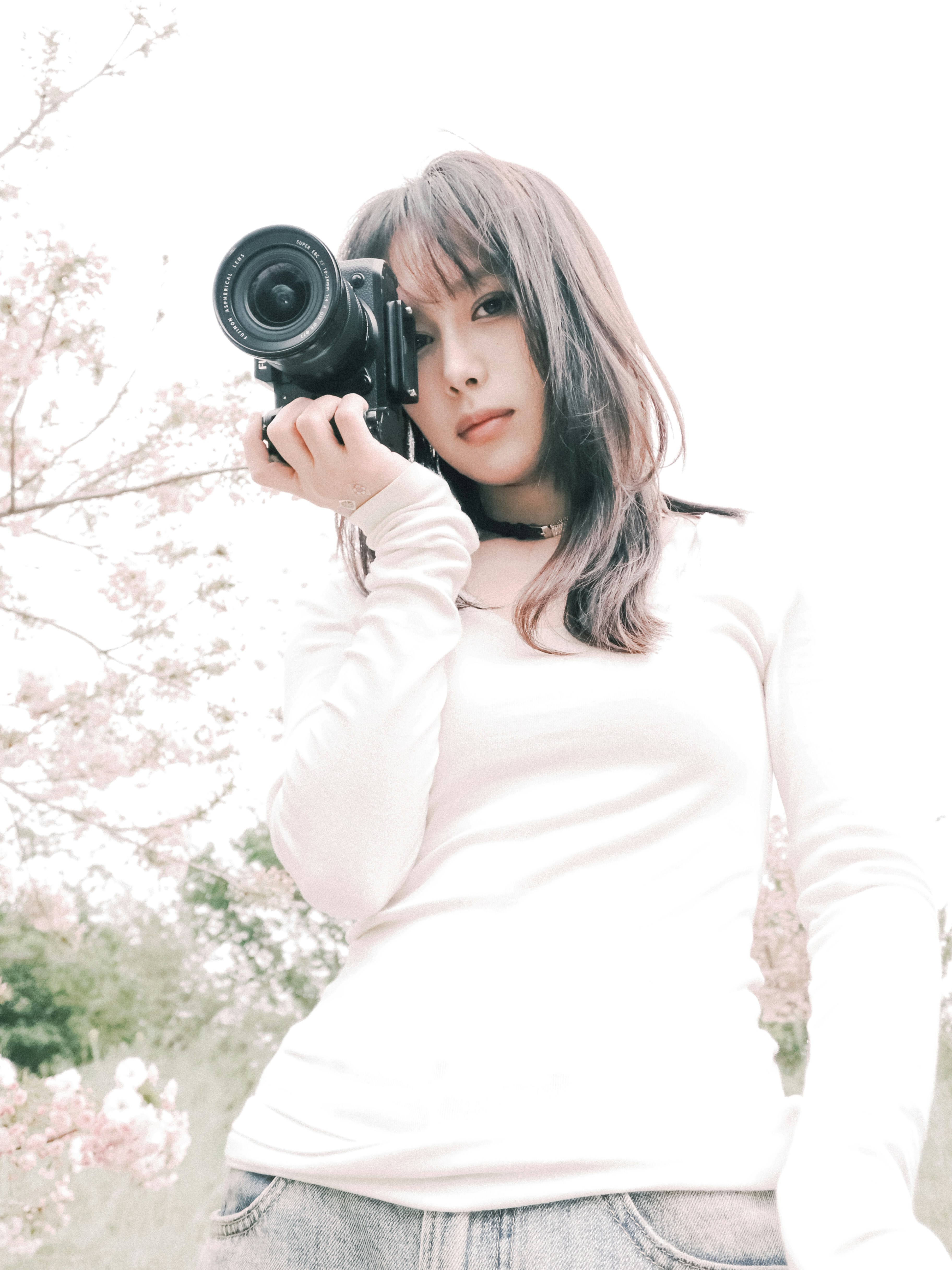 Woman holding camera with cherry blossoms