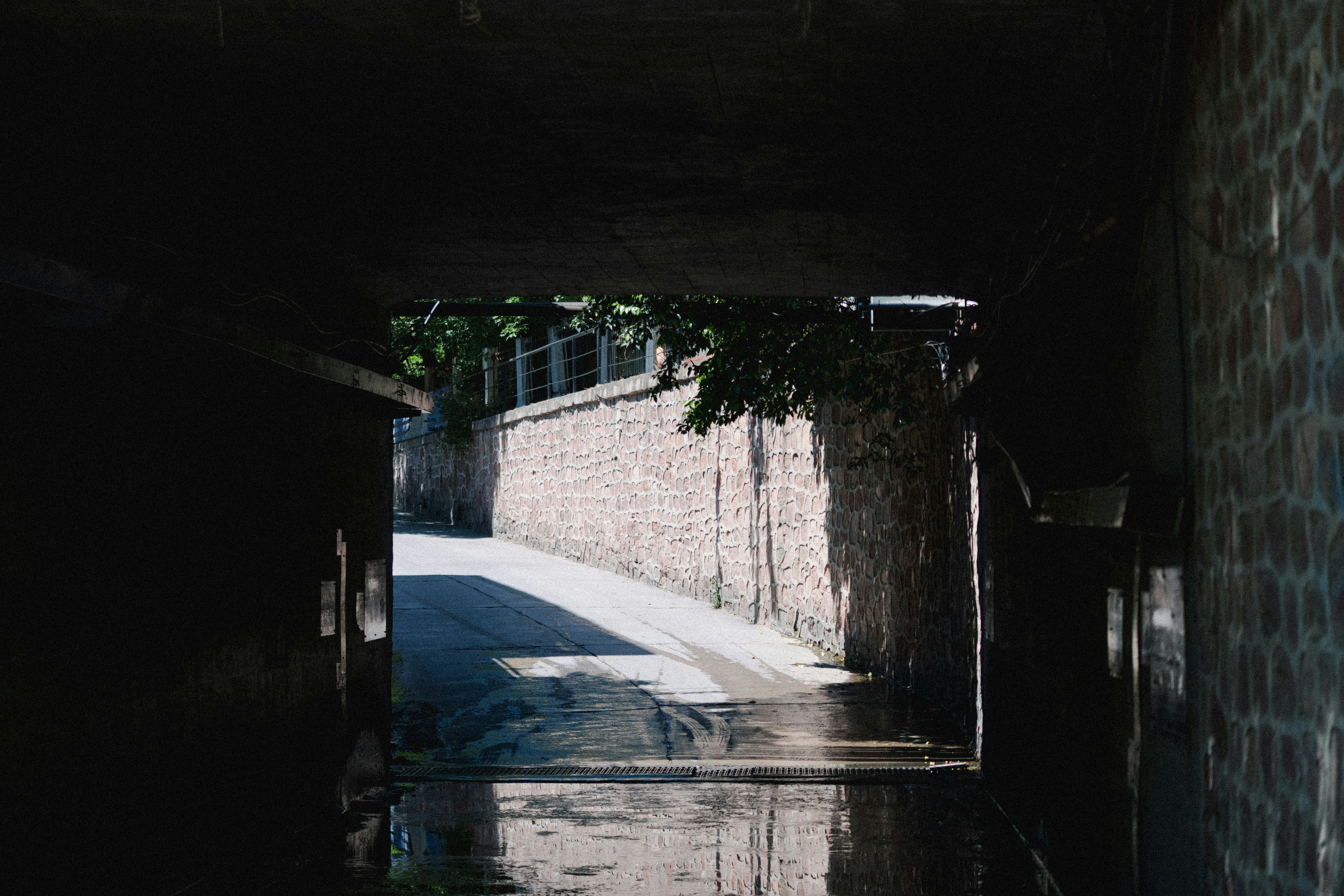 View through a dark tunnel to a sunlit brick wall