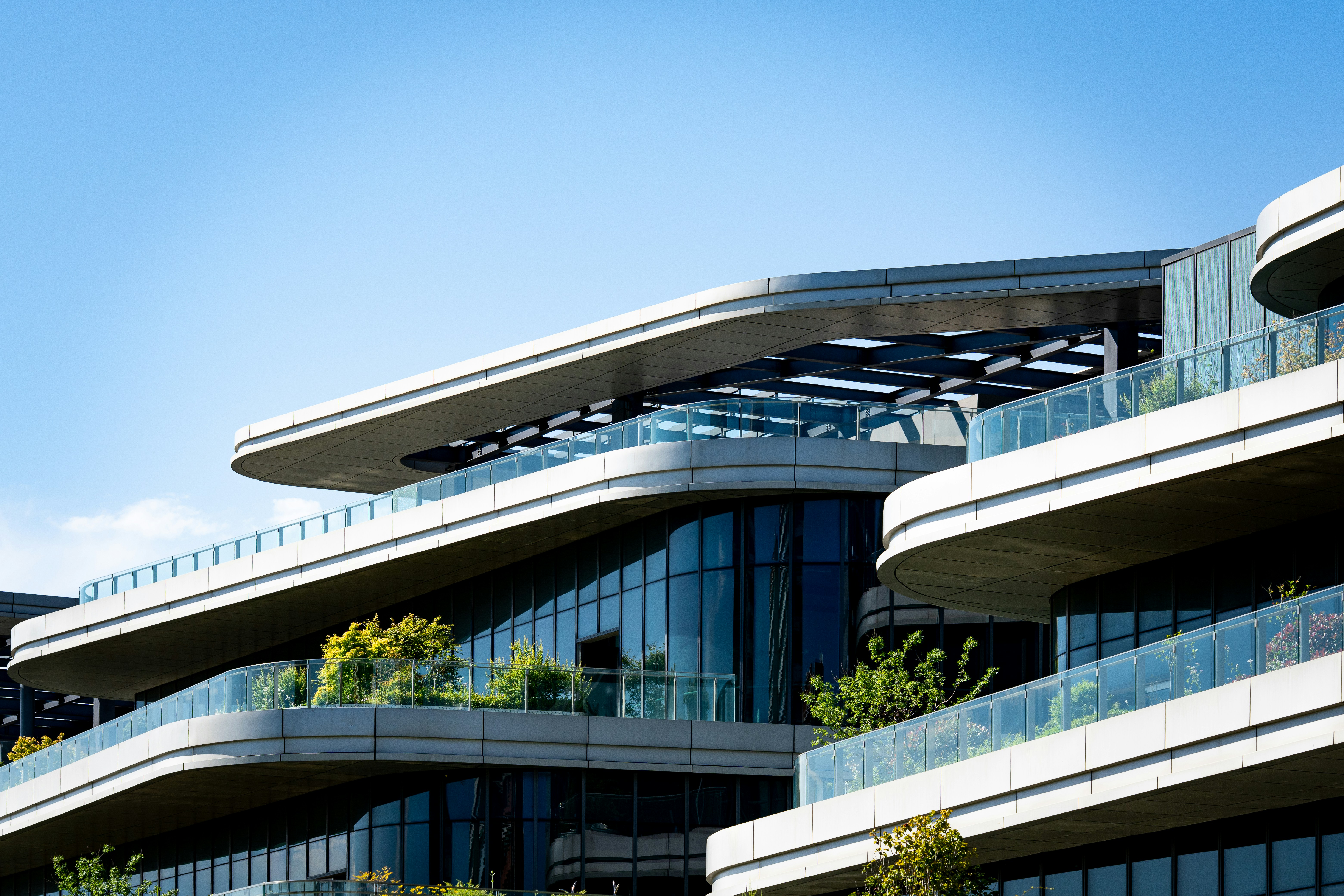 Modern architectural building with glass balconies and greenery.
