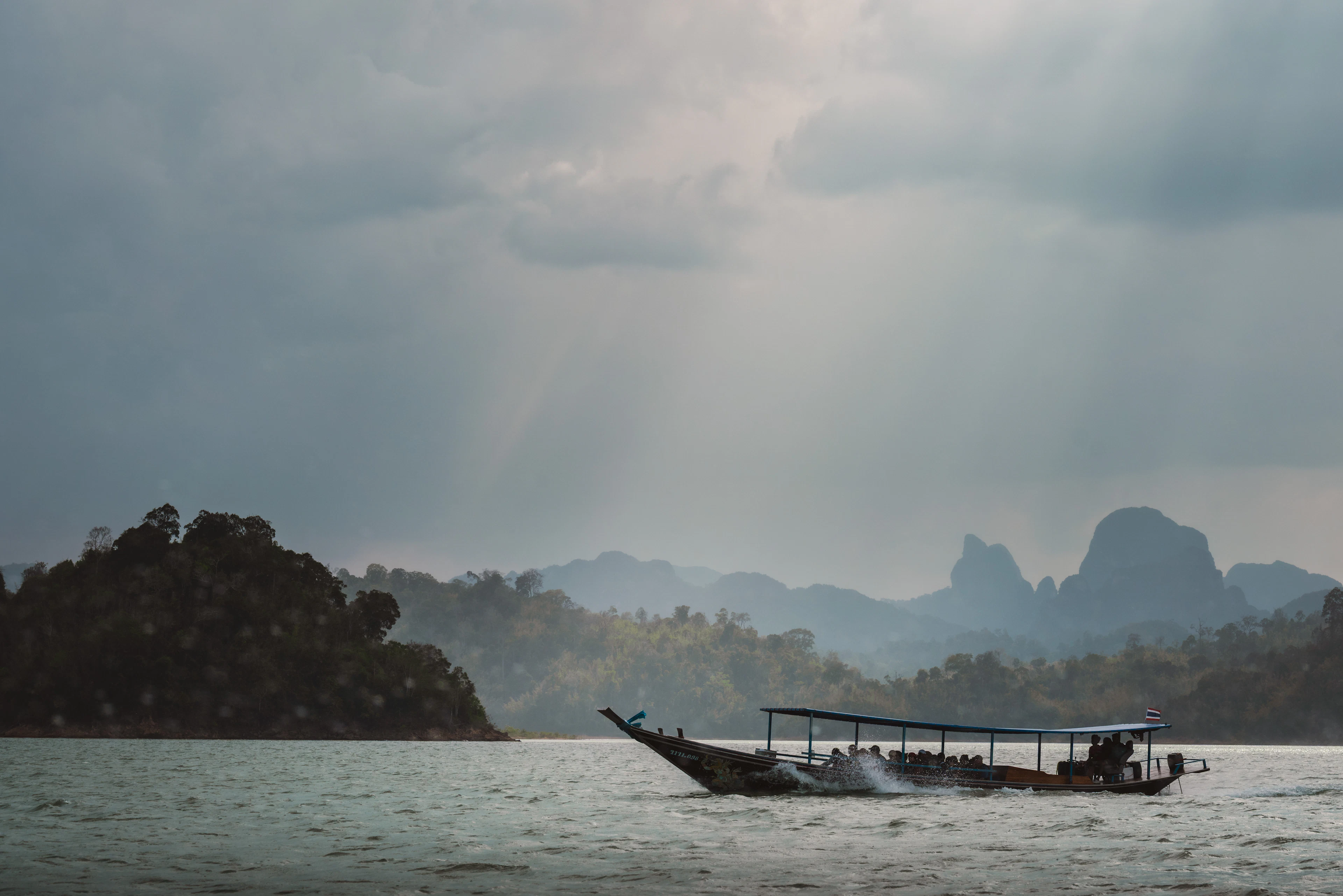 A longtail boat on a misty lake among limestone mountains in Khao Sok National Park