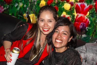 Two smiling women with colorful floral background