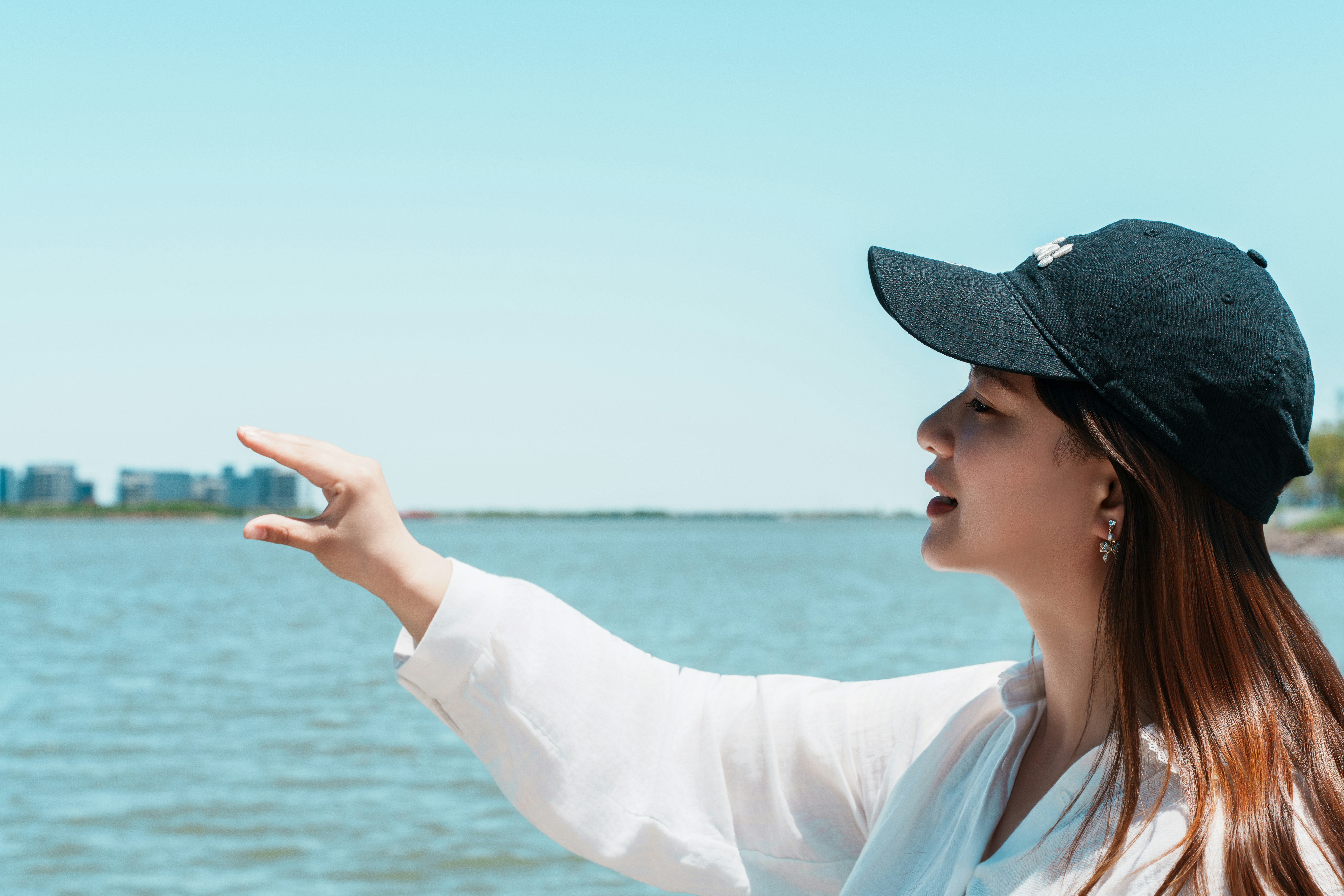 Woman in baseball cap reaches out over water