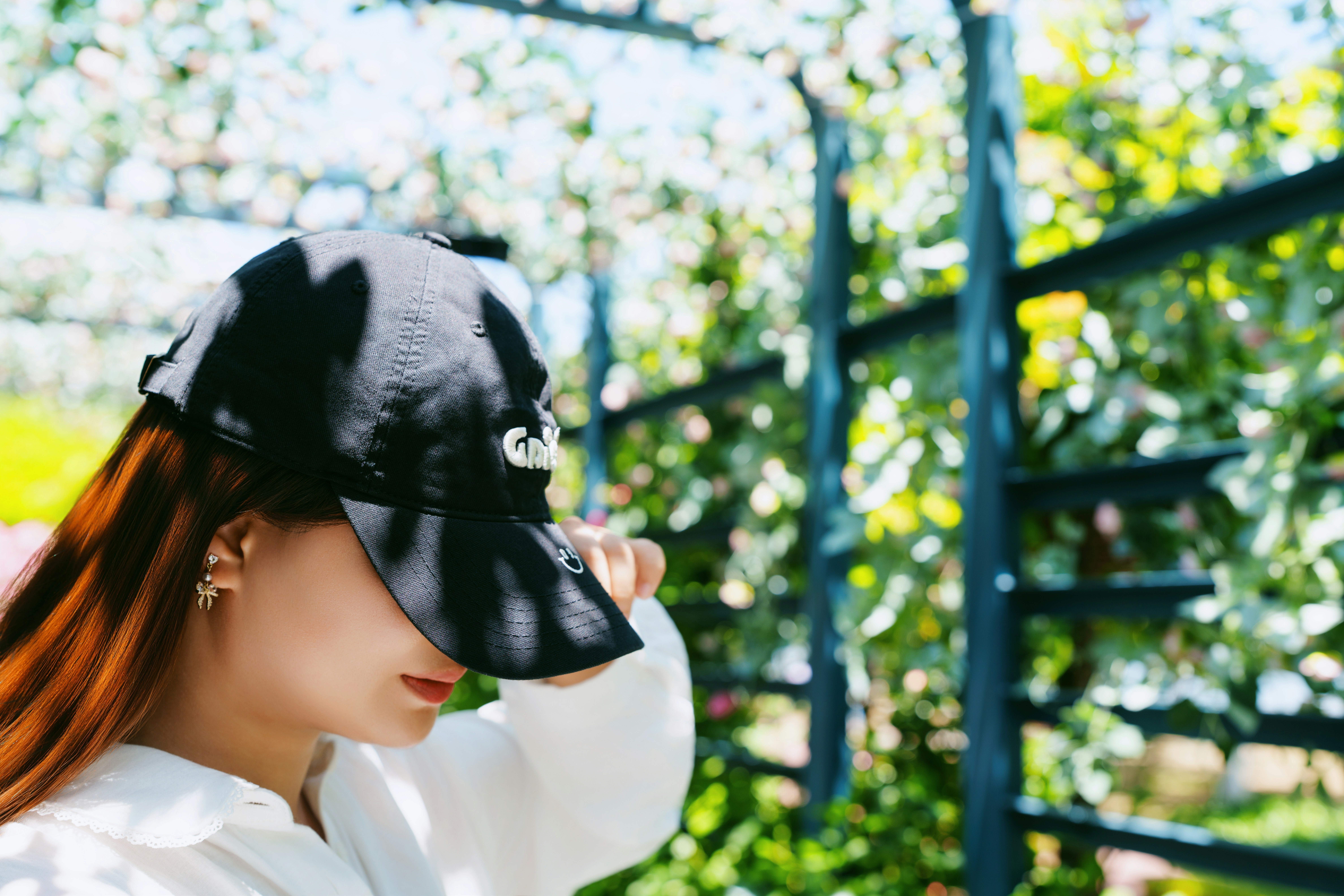 A woman wearing a baseball cap and white shirt.
