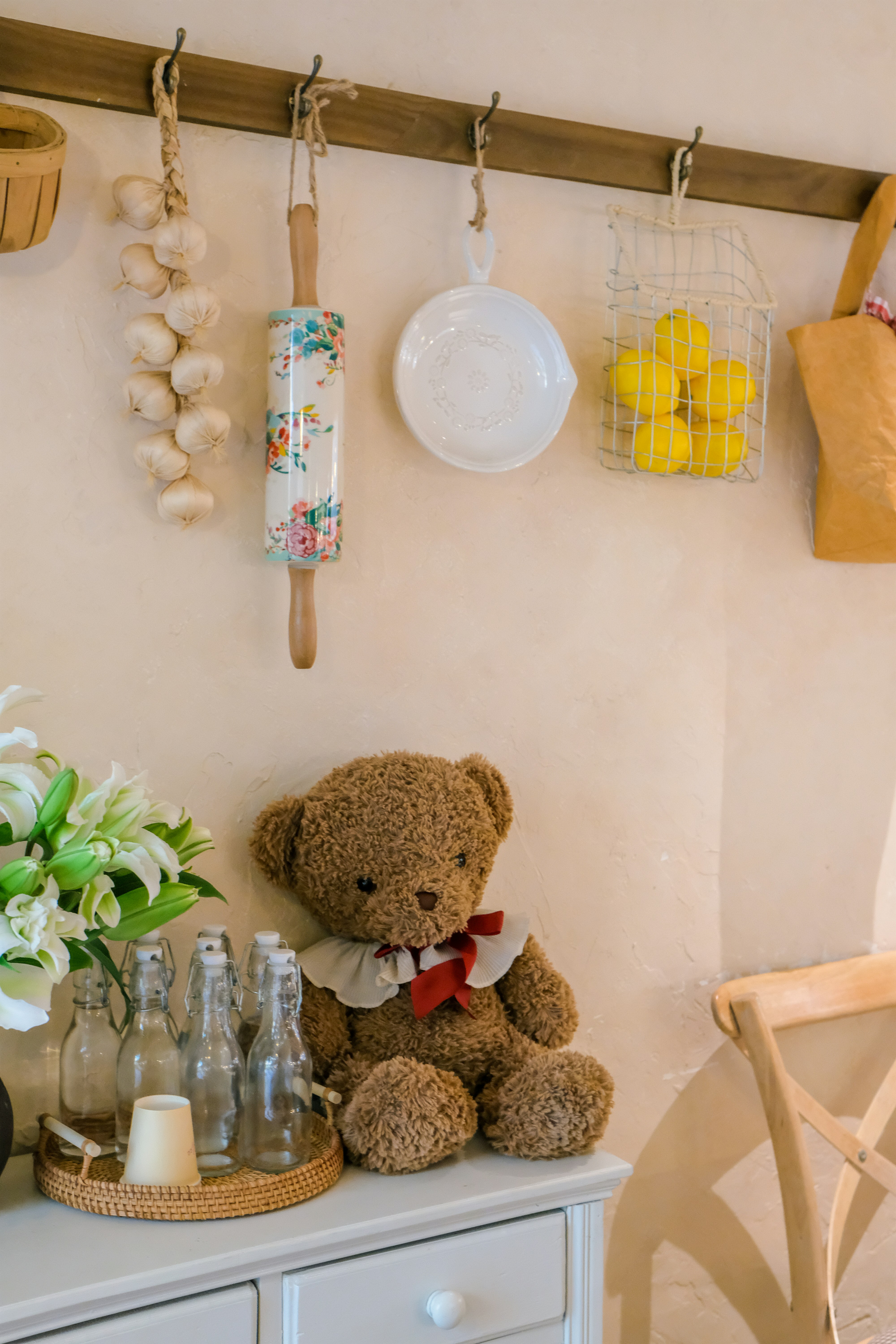 Osito de peluche con flores y utensilios de cocina en la estantería