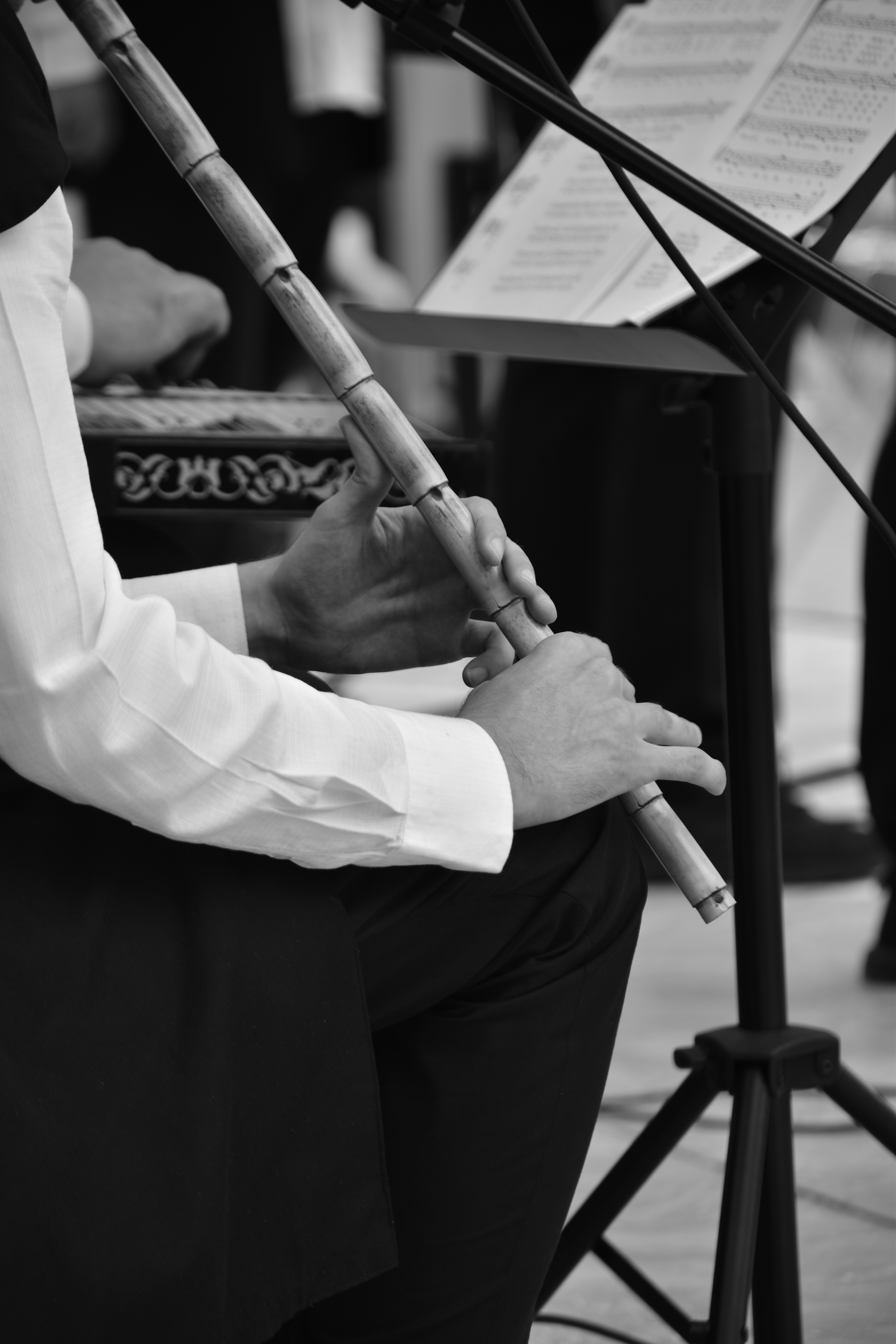 Músico tocando flauta de bambu com partitura.