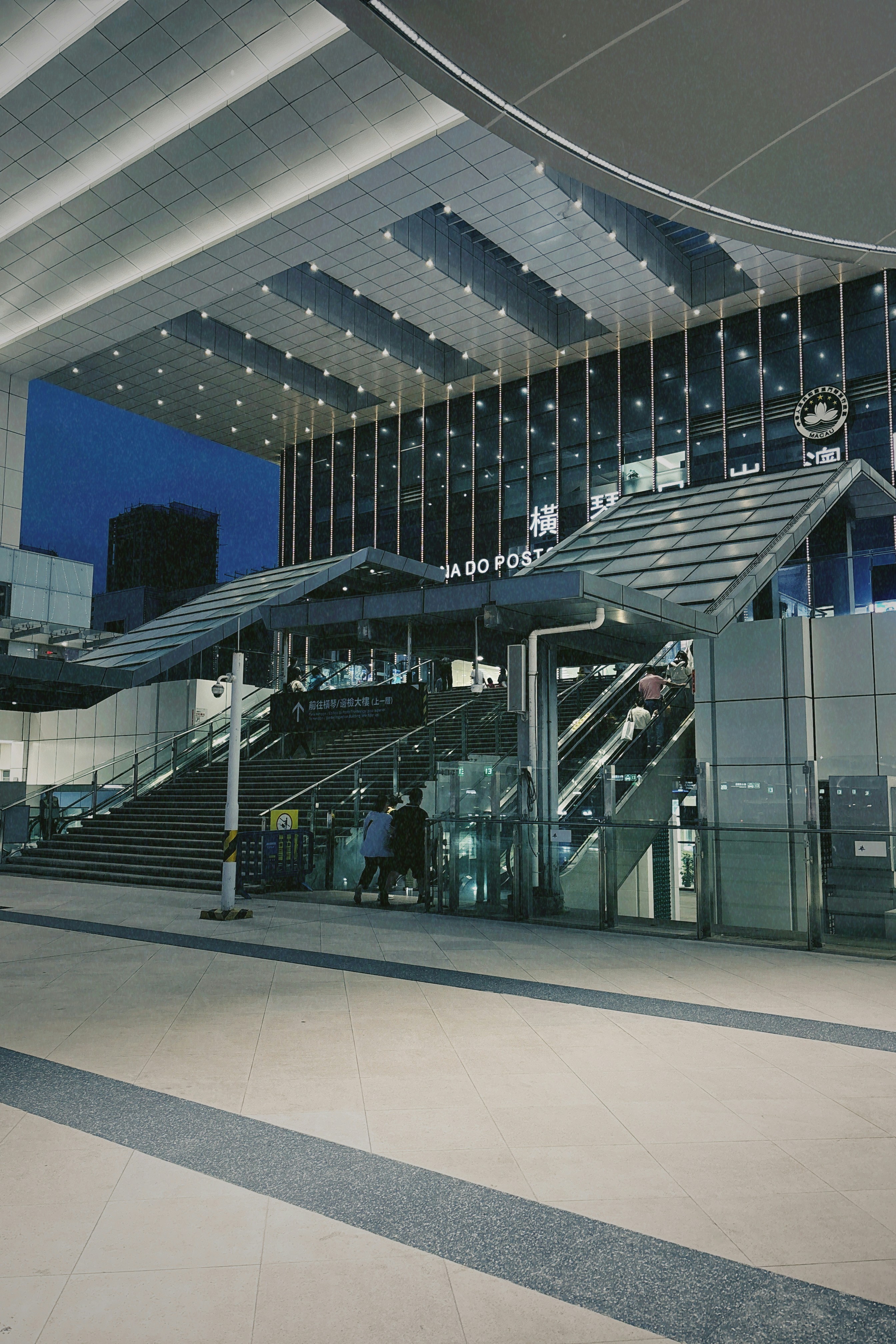 Moderner Bahnhofseingang mit Rolltreppen und Treppen.