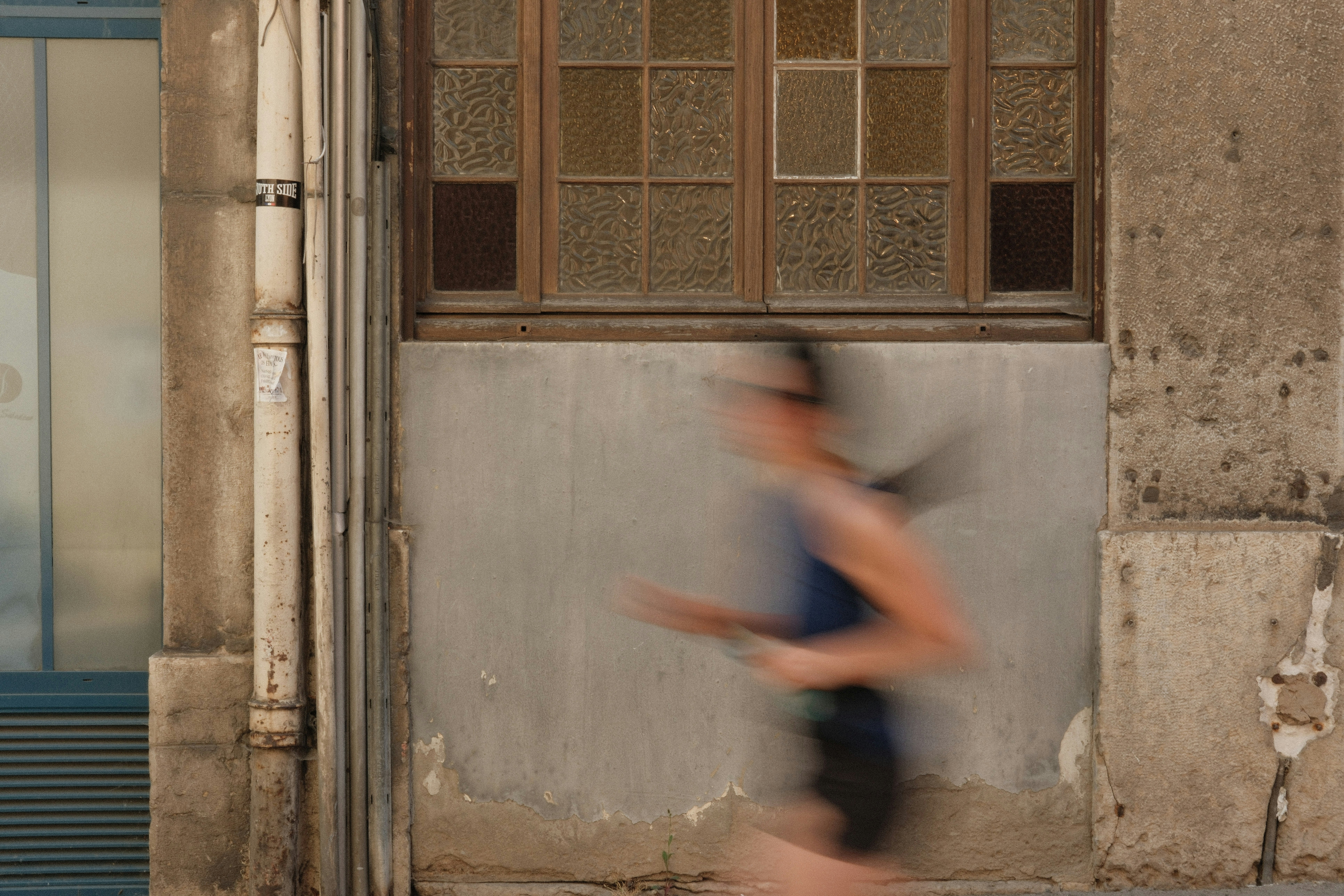 Woman running past a weathered building wall