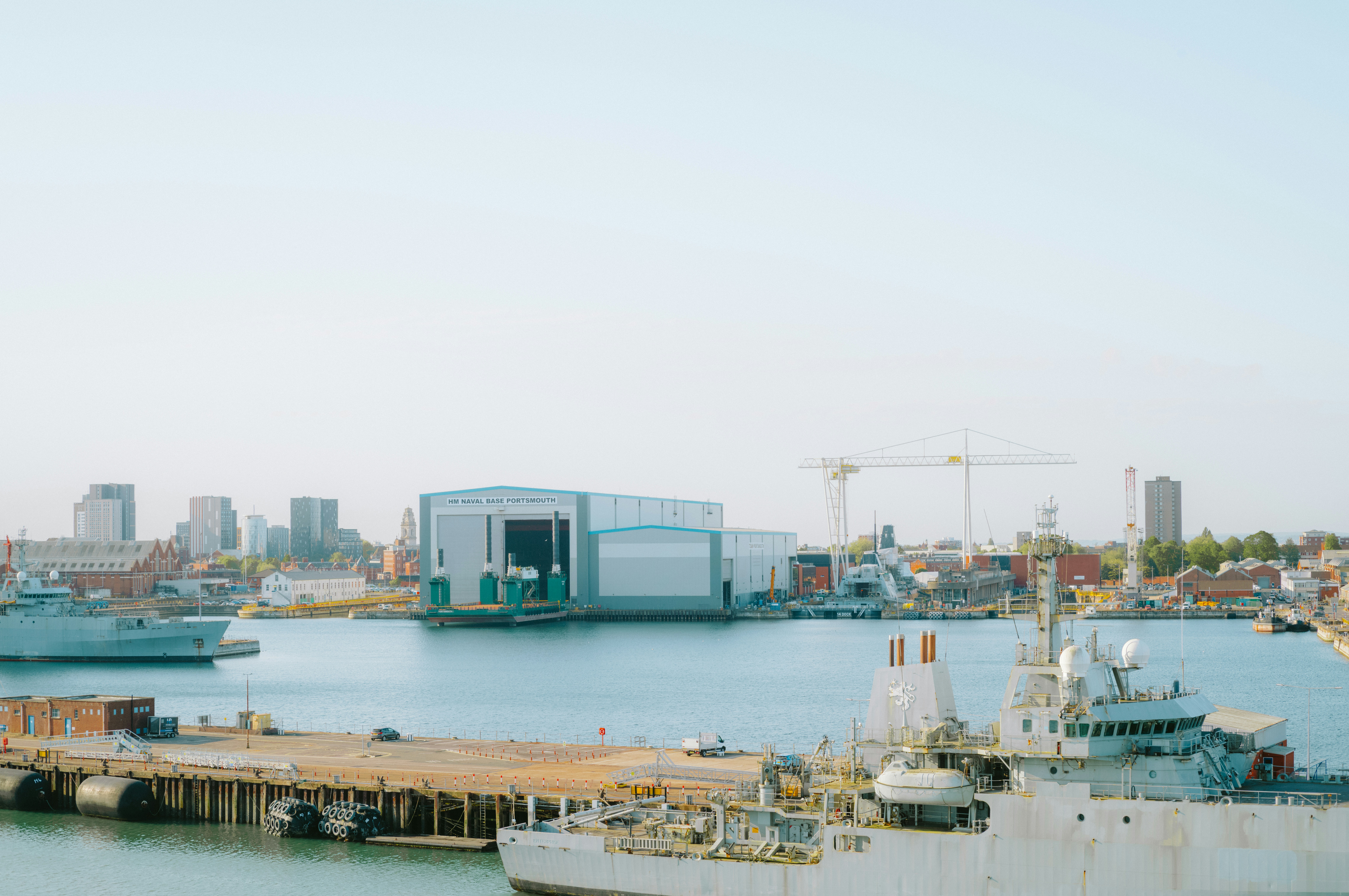 Ships docked in a harbor with industrial buildings.