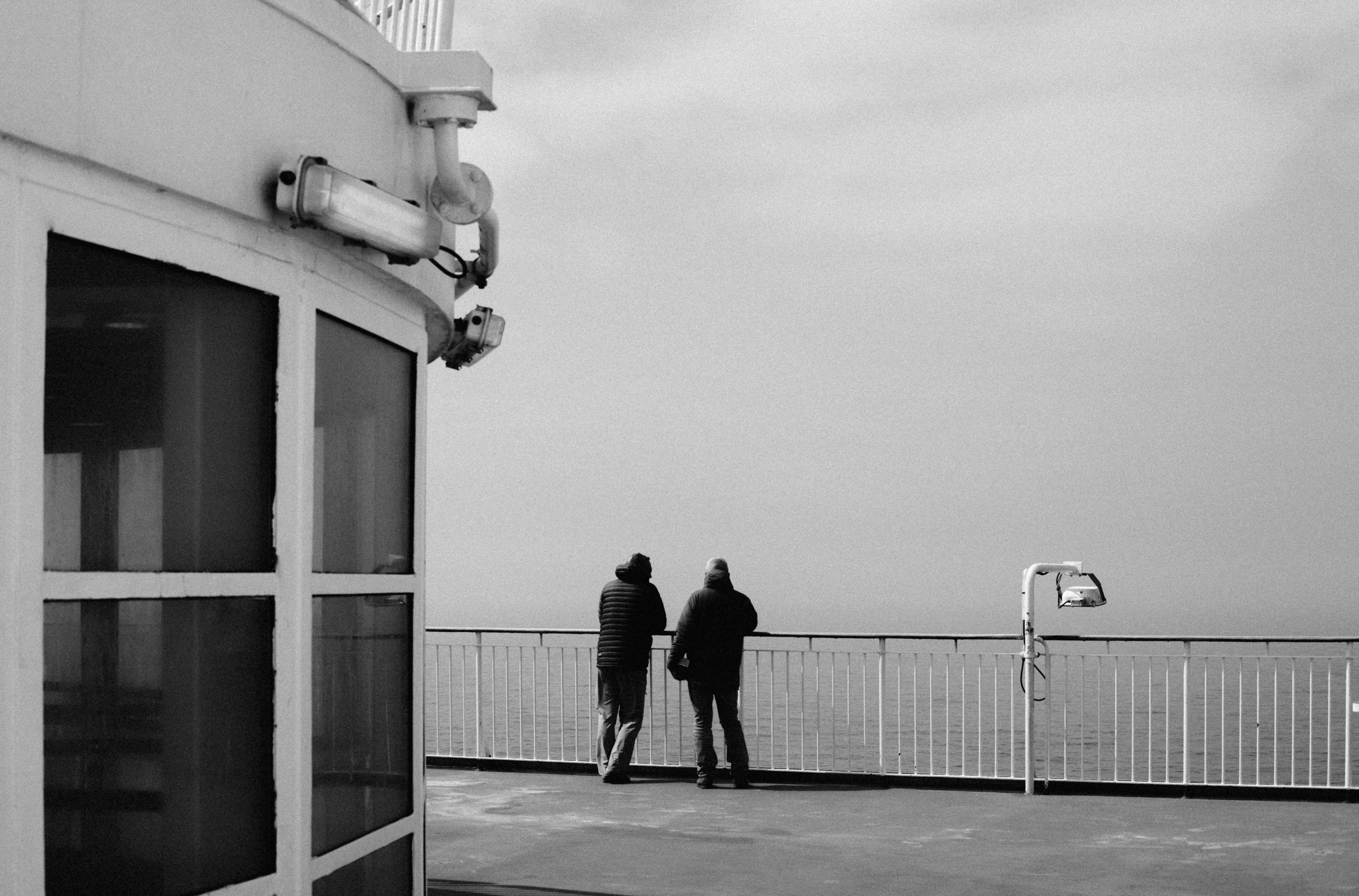 Two people stand on a deck overlooking the ocean
