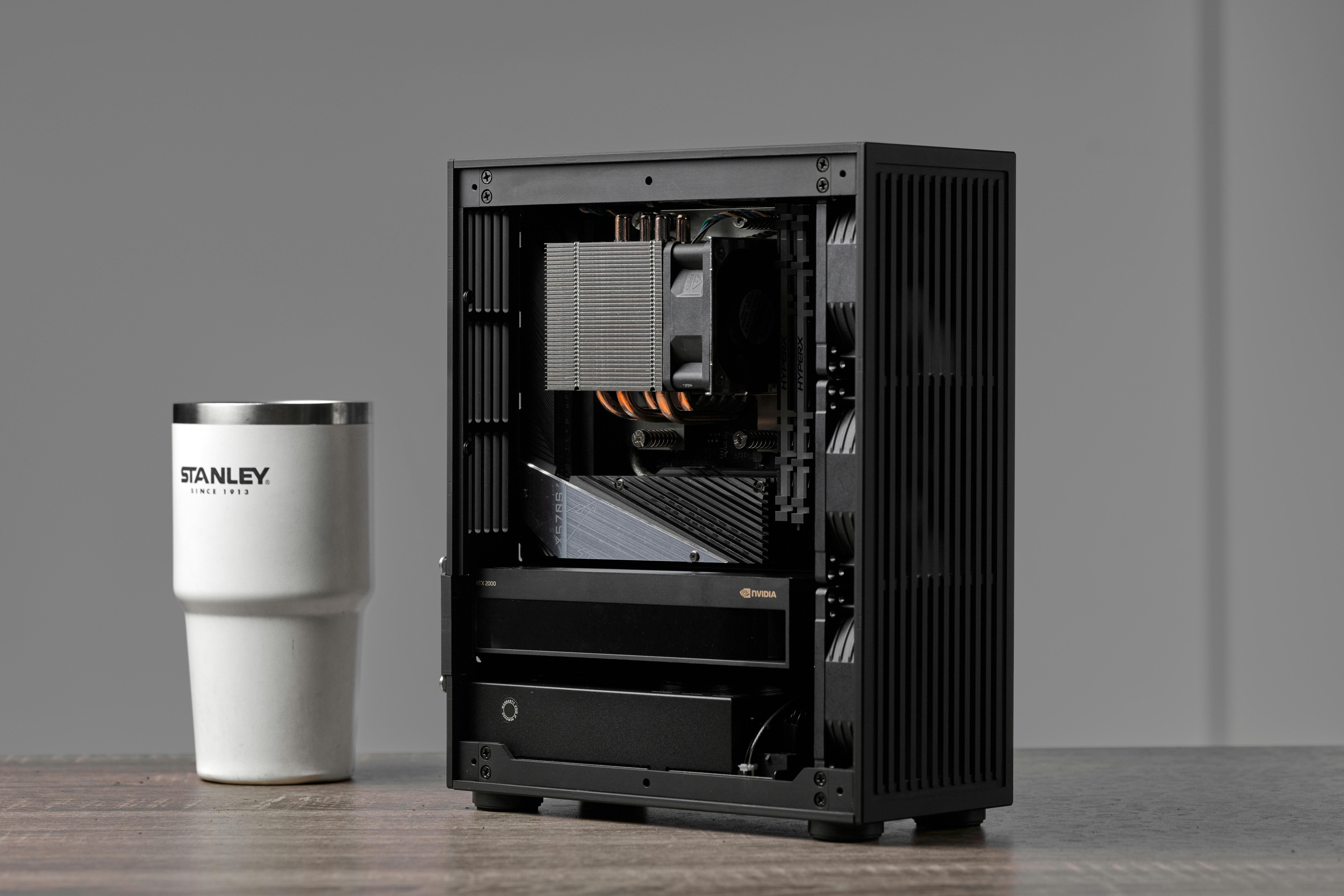 A white stanley tumbler next to an open computer case.