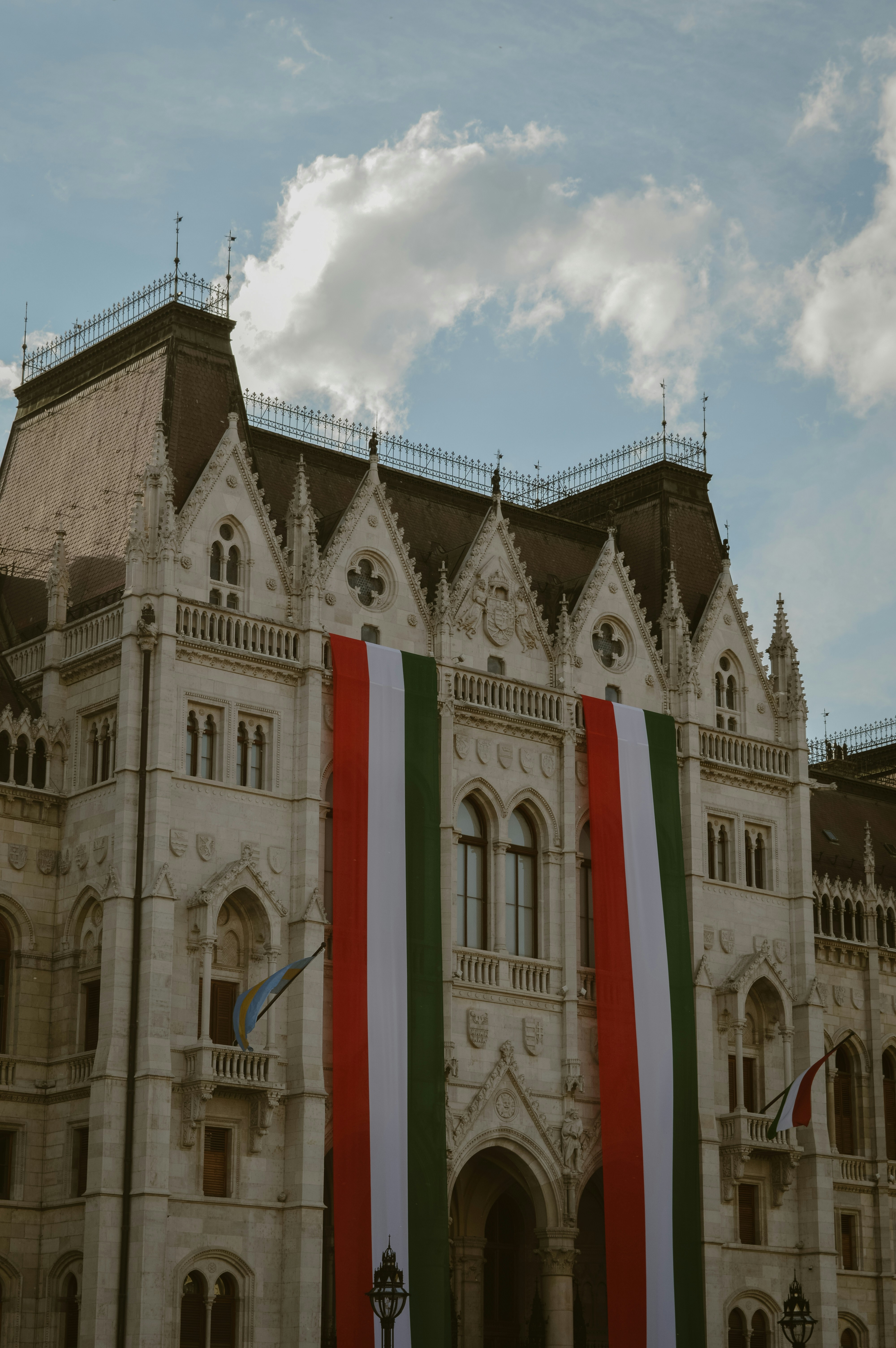 Ornate building displaying a large hungarian flag.