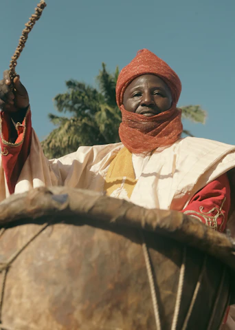 Man in red turban playing a traditional drum