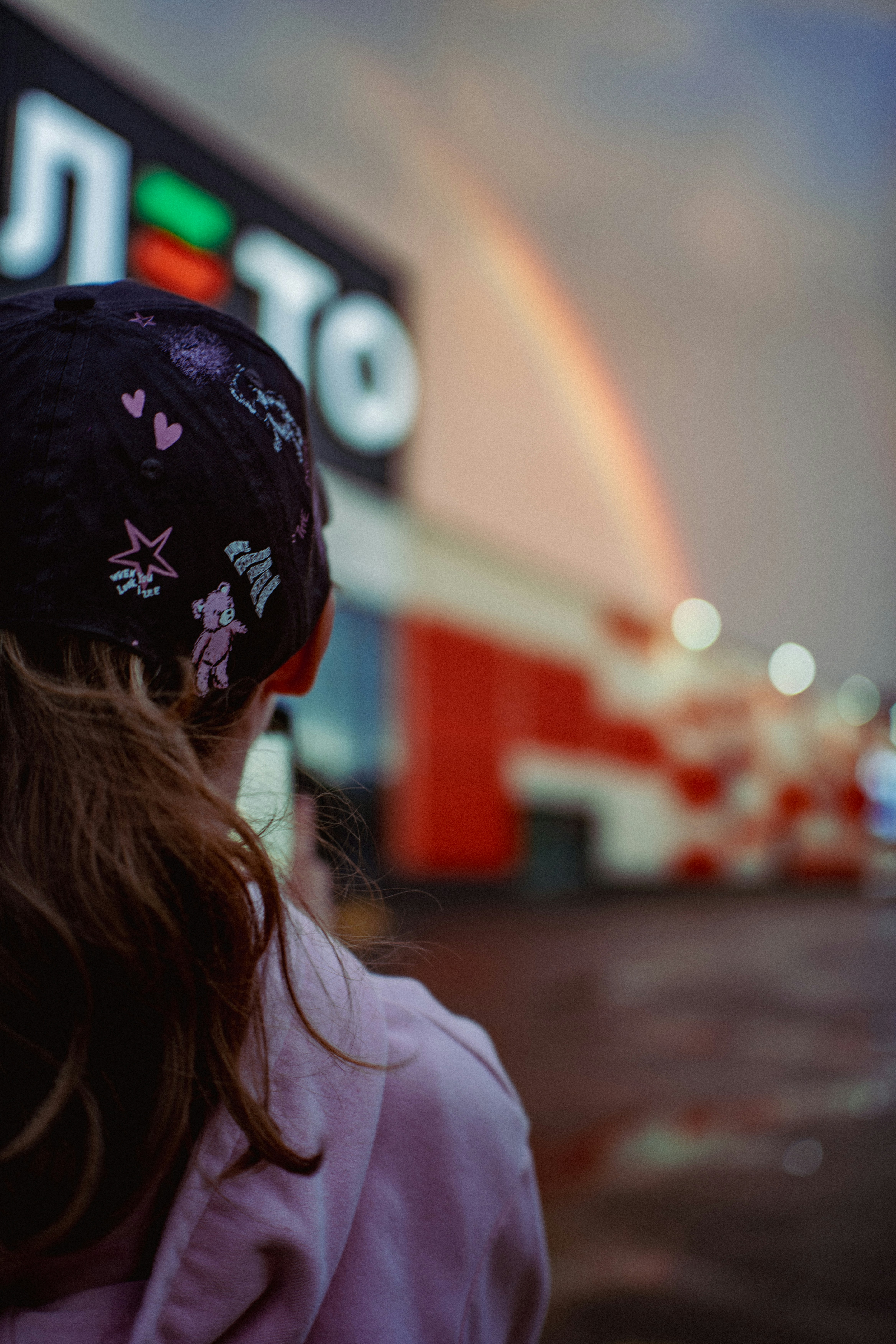 Child watches a rainbow over a building