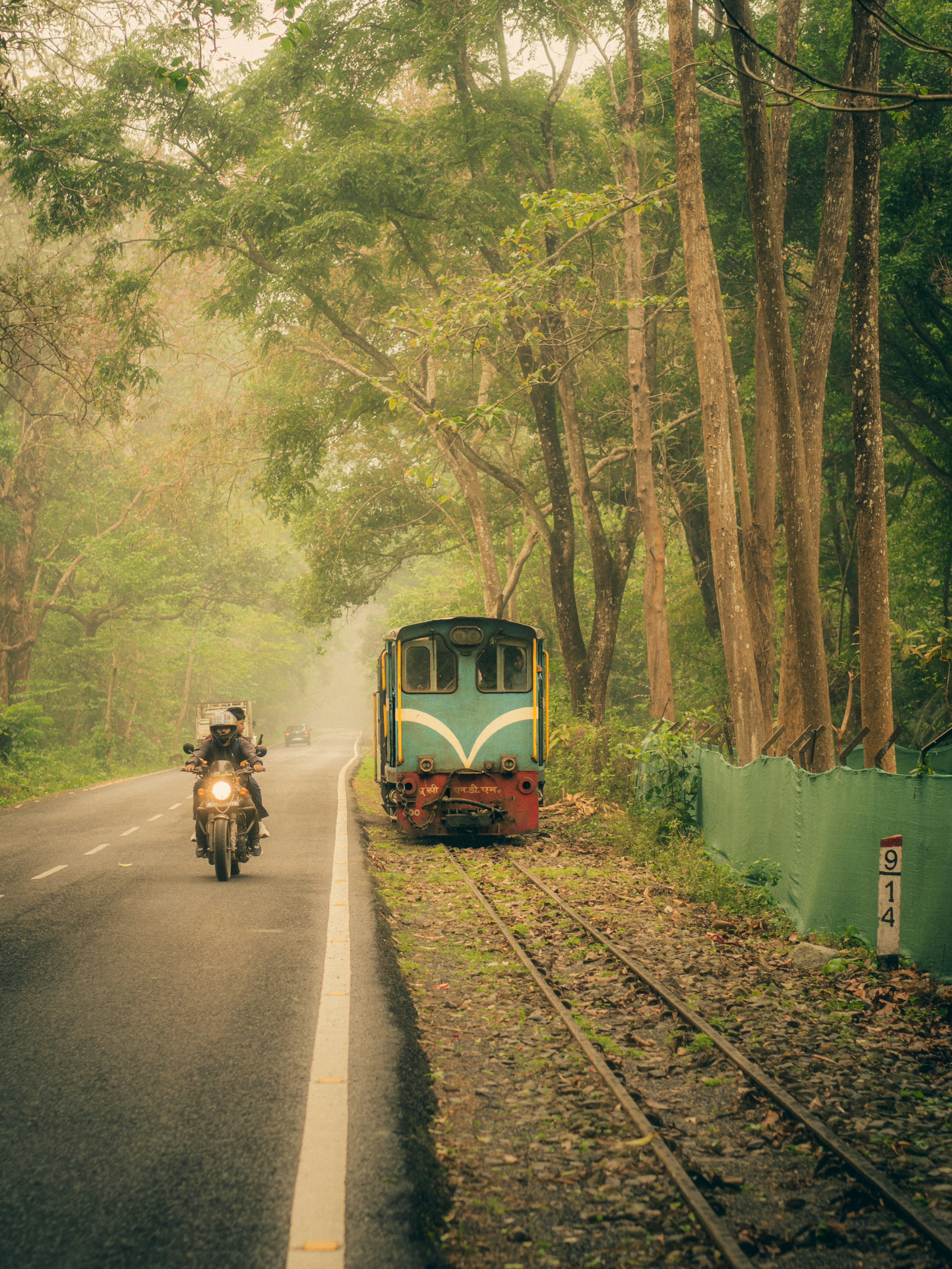 バイク乗りが森の中のヴィンテージ列車のそばを通り過ぎる。