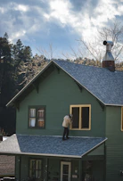 Person on roof painting a house window