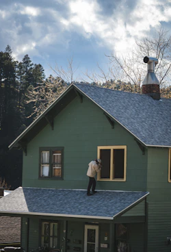 Person on roof painting a house window