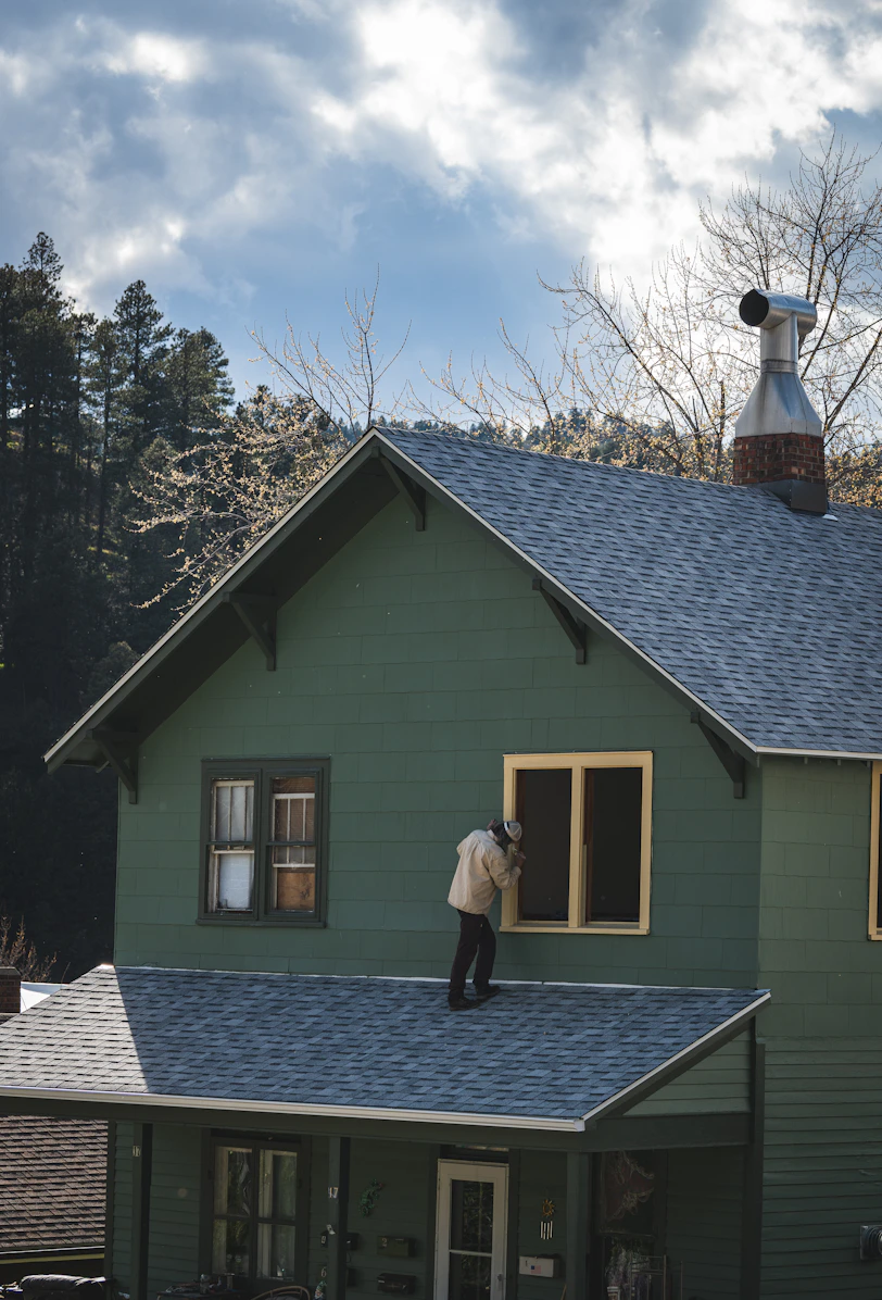Person on roof painting a house window