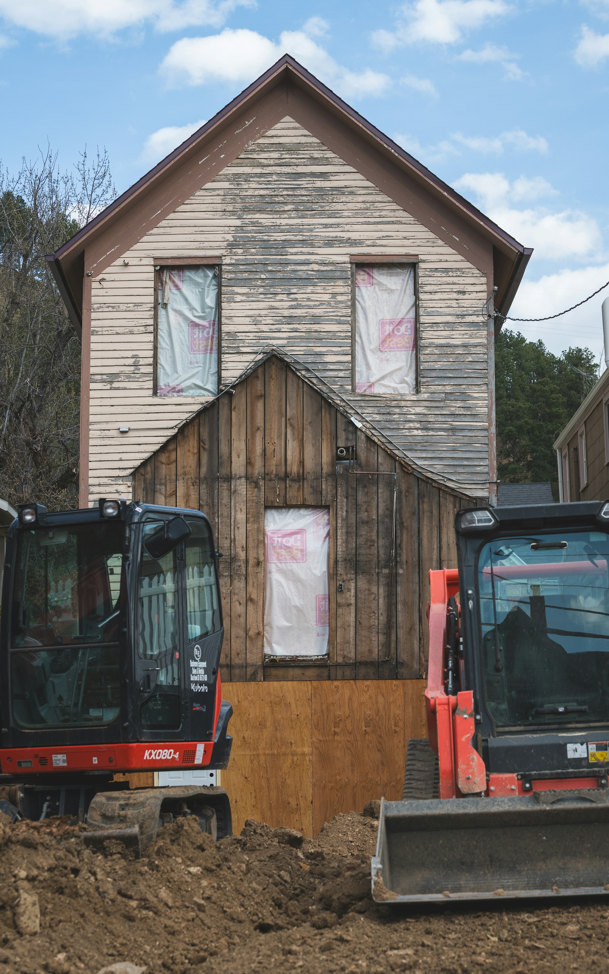 Excavators positioned in front of an older house undergoing foundation repair work