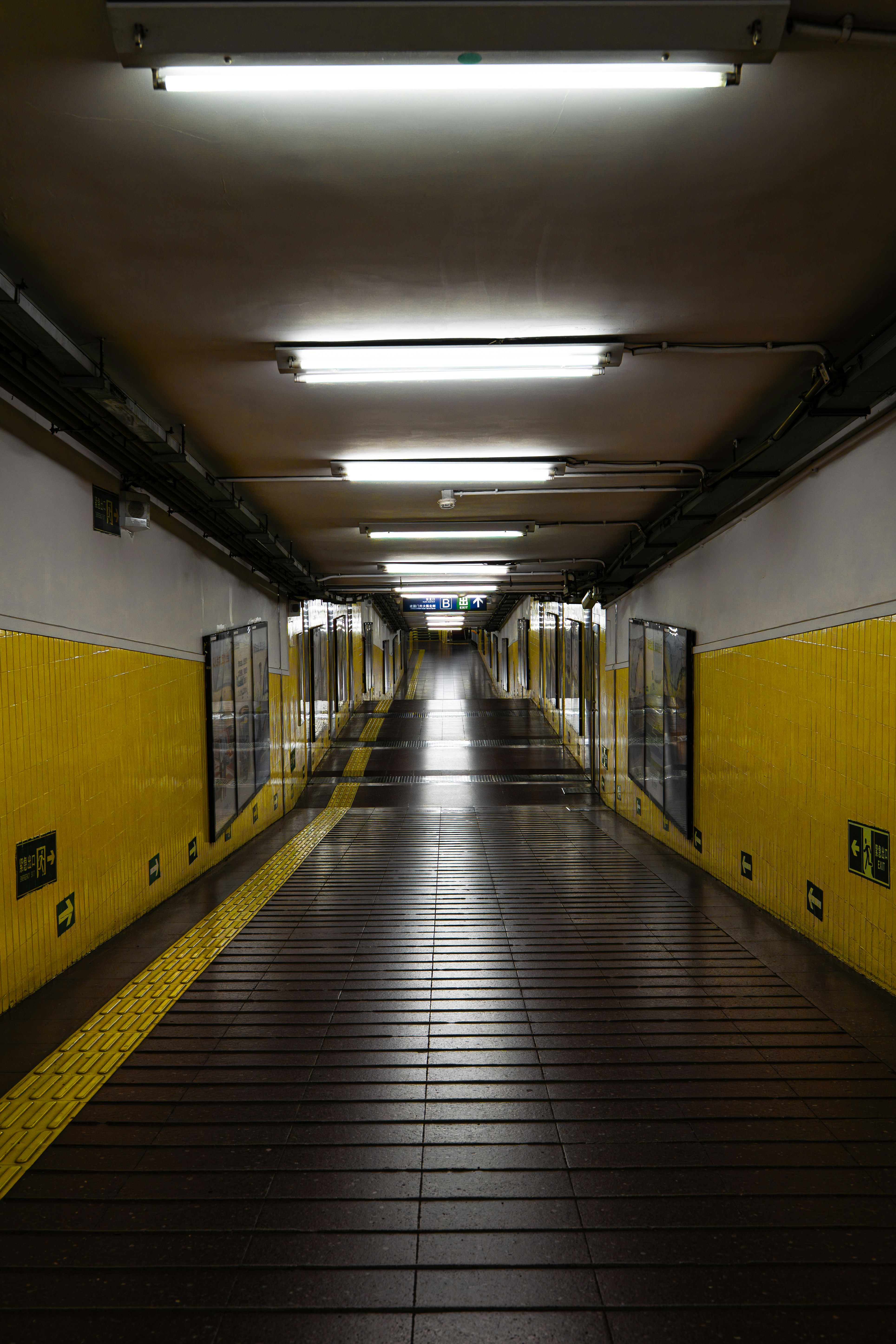 Un lungo tunnel della metropolitana illuminato con pareti gialle.