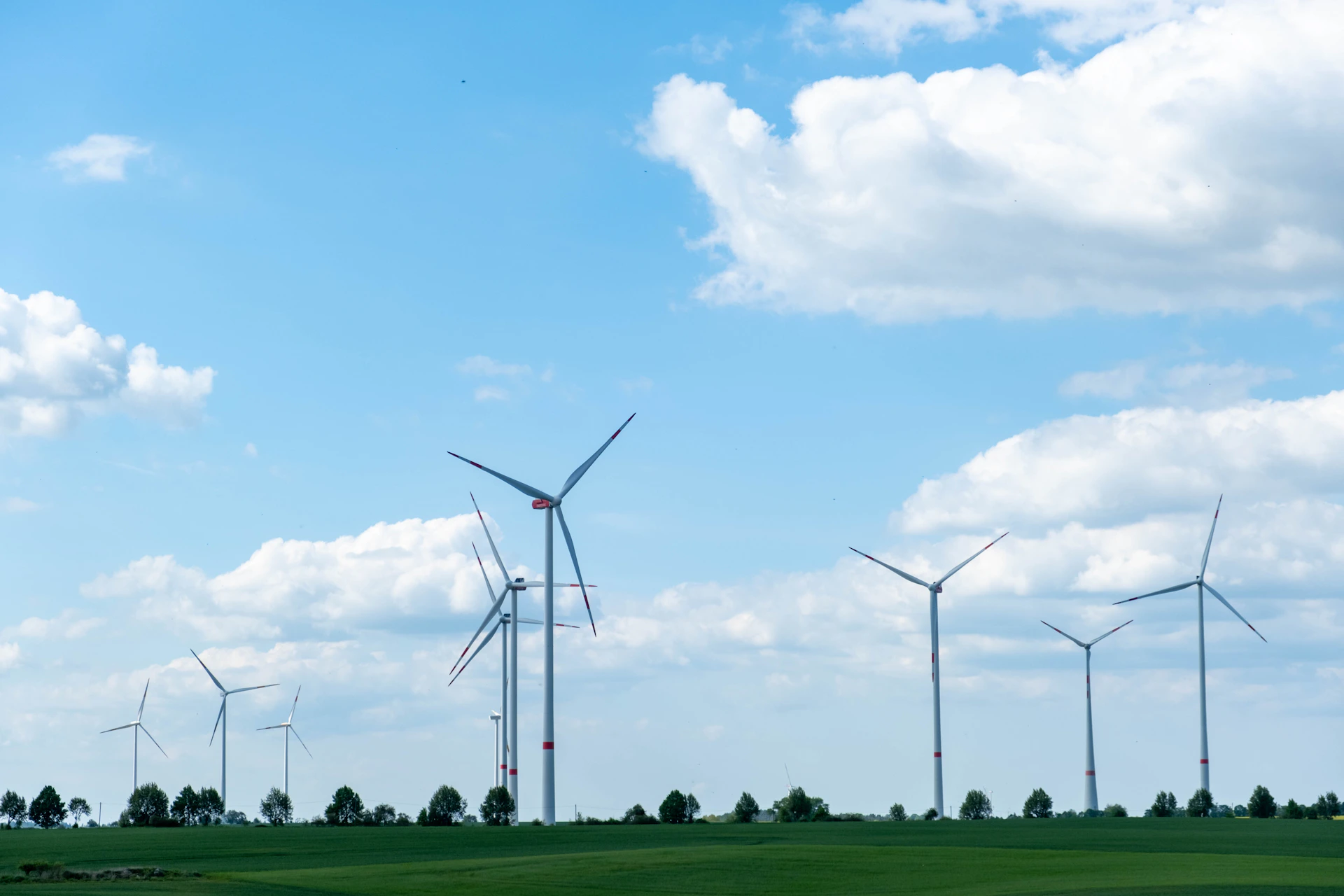Wind turbines stand tall against a cloudy blue sky.
